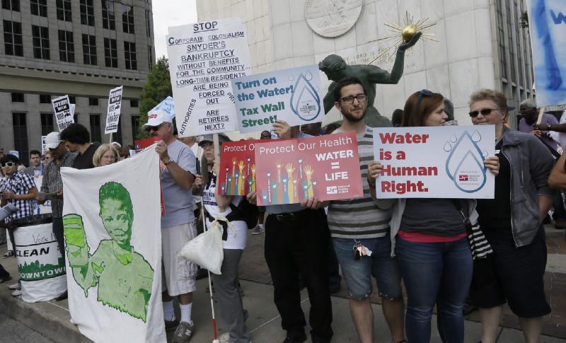 People stand outside Detroit City Hall, protesting thousands of residential water-service shutoffs by Detroit’s water department, during a rally in Detroit, Thursday, July 24, 2014. CREDIT: AP Photo