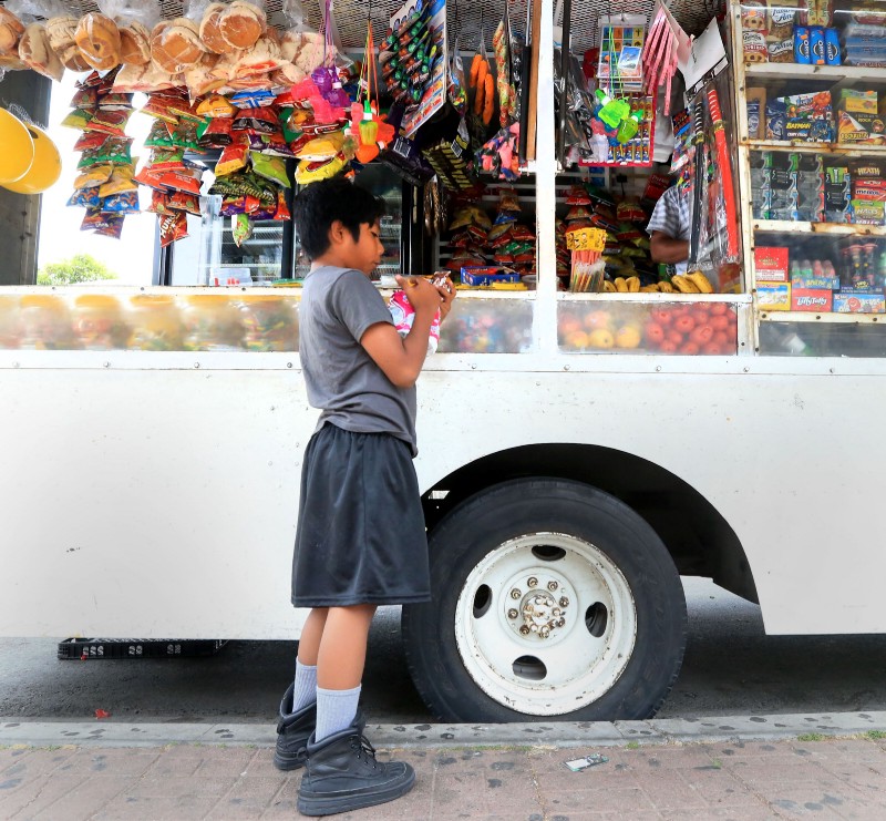 Peter Gaspar buys a snack and other items from a neighborhood food truck on Townsend Street in Santa Ana, Ca. CREDIT: Daniel A. Anderson for ThinkProgress