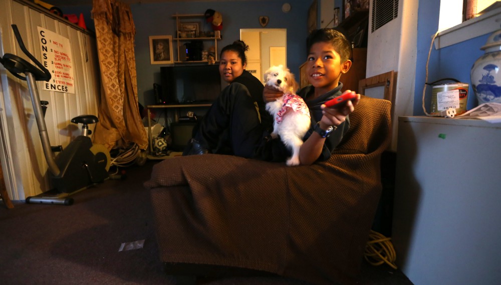 Cesar Gaspar, dressed and ready for school, enjoys a moment with his pet dog and his older sister before heading to class. CREDIT: Daniel A. Anderson for ThinkProgress