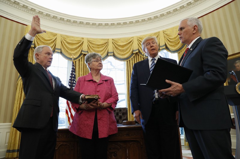 President Donald Trump watches as Vice President Mike Pence administers the oath of office to Attorney General Jeff Sessions, accompanied by his wife Mary, Thursday, Feb. 9, 2017, in the Oval Office of the White House in Washington. CREDIT: AP Photo/Pablo Martinez Monsivais