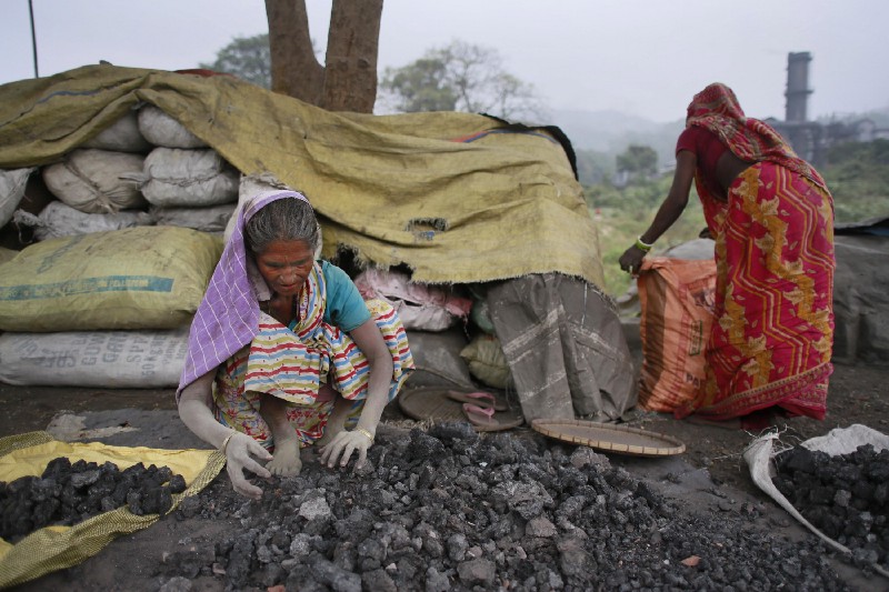 Indian women use bare hands to pick reusable pieces from heaps of used coal discarded by a carbon factory in Gauhati, India. CREDIT: AP Photo/ Anupam Nath
