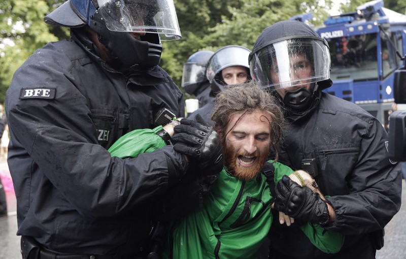 Police officers carry a demonstrator who blocked a street on the first day of the G-20 summit in Hamburg, northern Germany, Friday, July 7, 2017. CREDIT: AP Photo/Matthias Schrader