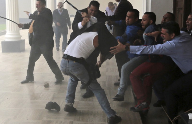 Opposition lawmakers brawl with pro-government militias who are trying to force their way into the National Assembly during a special session. CREDIT: AP Photos/Fernando Llano
