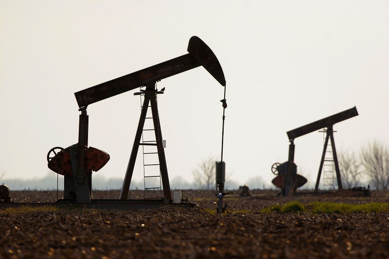 Oil pump jacks are seen at sunset in a corn field near Divernon, IL. CREDIT: AP Photo/Seth Perlman, file