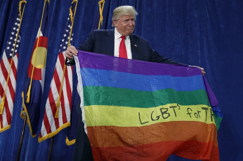 Trump holds up a rainbow “LGBTs for Trump” flag at a 2016 rally in Colorado. CREDIT: AP Photo/Evan Vucci