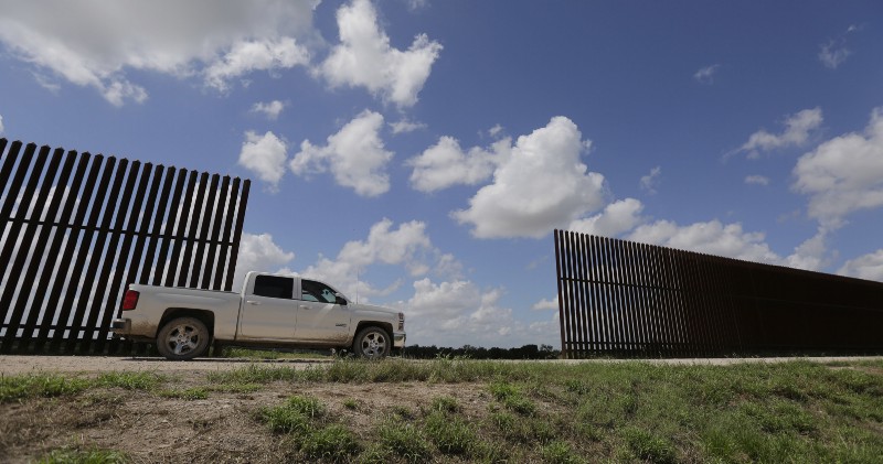 A farmer passes along a borer fence that divides his property, Tuesday, in Mission, Texas. CREDIT: AP Photo/Eric Gay