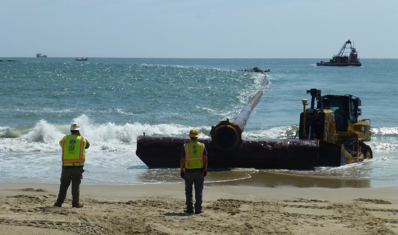 Workers position pipe to transport sand excavated from the Atlantic Ocean floor to the beach in Duck, North Carolina. CREDIT: Mark Hand/ThinkProgress