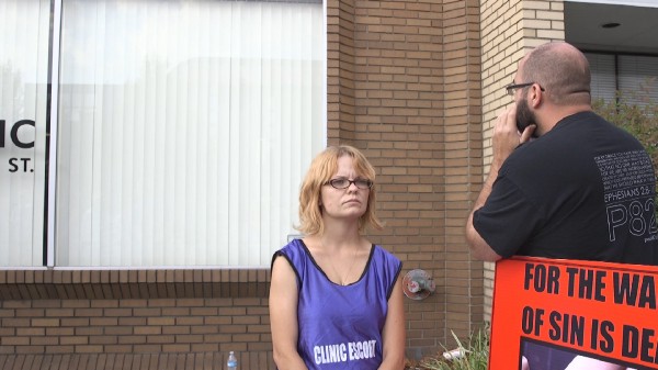 A protester shouts through the window at the patient inside the E.M.W clinic CREDIT: Katelyn Marmon