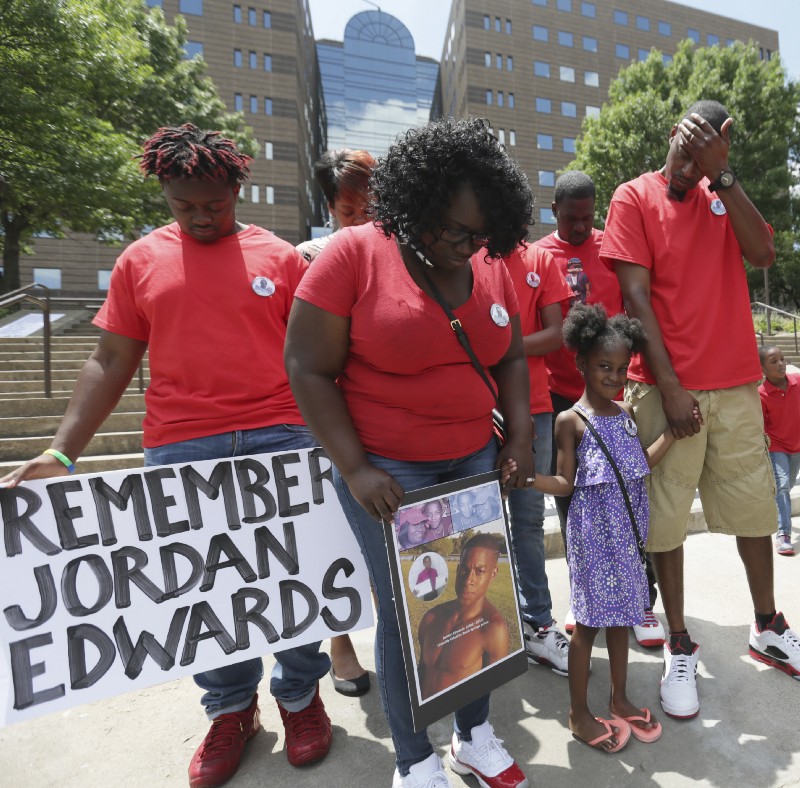 Jordan Edwards’ mother Charmaine Edwards, center, holds a photo of her slain son as she stands with her son Vidal Allen, left, and husband Odell Edwards, right, and other family members during a prayer outside the court house in Dallas, May 13, 2017. CREDIT: AP Photo/LM Otero