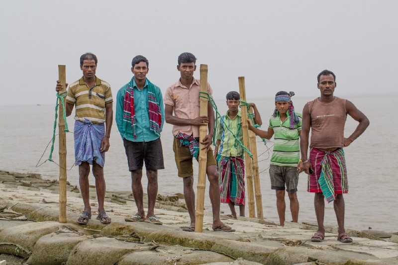 In this Nov. 18, 2015 photo, Bangladeshis from nearby districts who have come to help build a dam pose for a photograph in the island district of Bhola, where the Meghna River spills into the Bay of Bengal, Bangladesh. Though Prime Minister Sheikh Hasina has been internationally recognized for raising awareness of climate-change issues, Bangladesh has no specific plan for dealing with its own people displaced by climate-related disasters, other than offering them temporary shelter. CREDIT: AP Photo/Shahria Sharmin