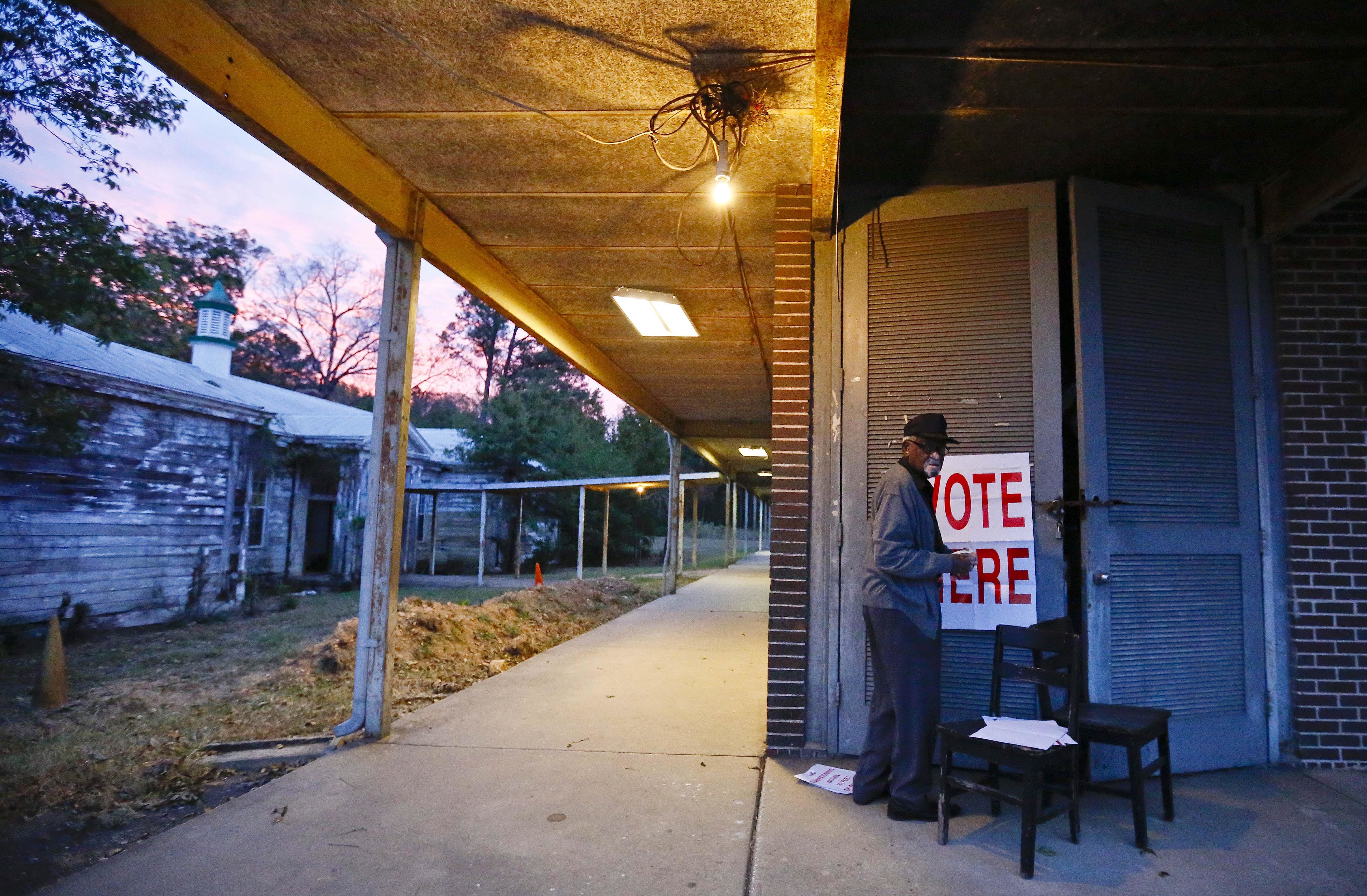 Volunteer Herman Hooks, 89 puts up a "Vote Here" sign at the Muscoda Community Center before the poles open for voting Tuesday, Nov. 8, 2016, in Bessemer, Ala. (AP Photo/Brynn Anderson)