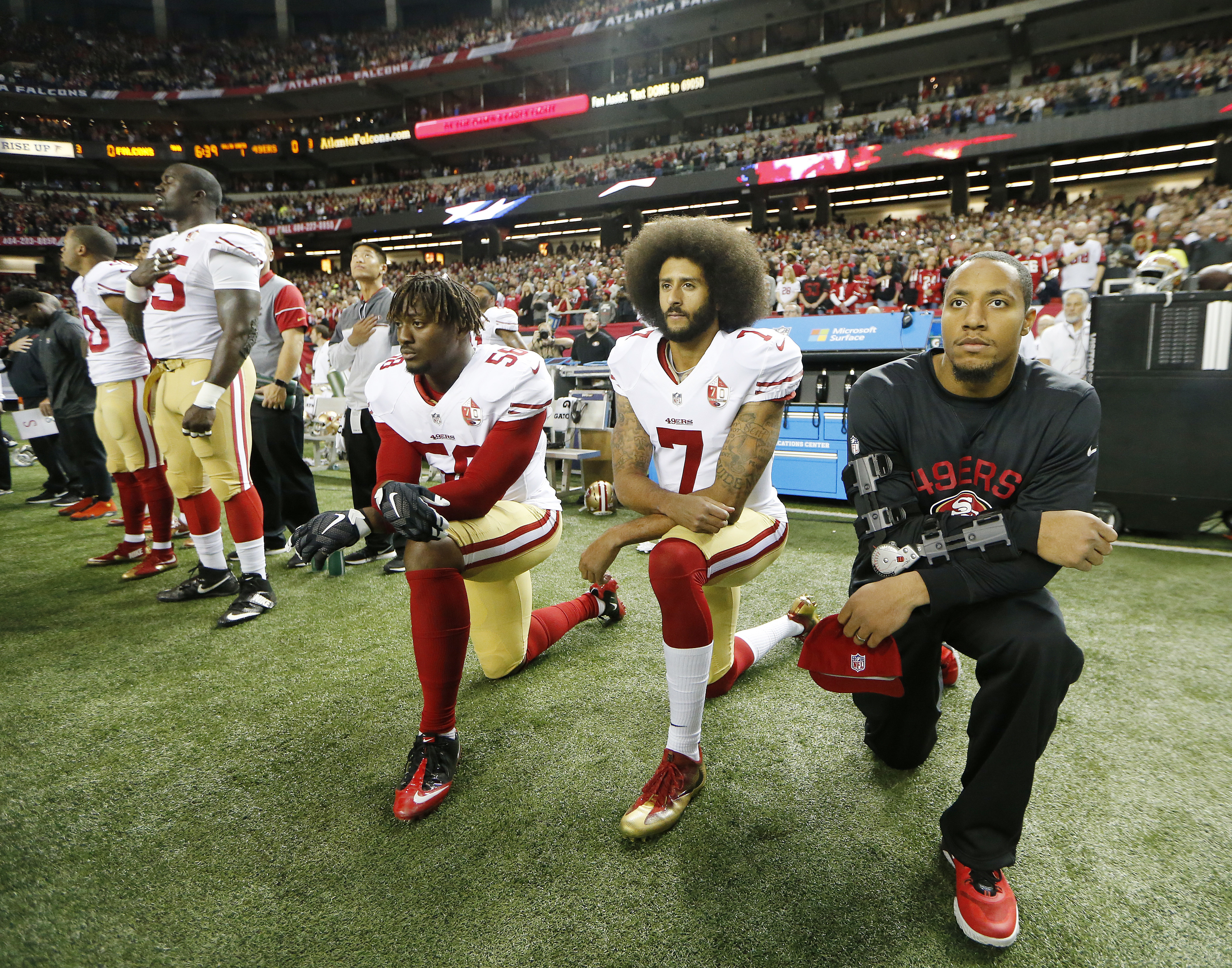 Colin Kaepernick (7) and Eli Harold (58) kneel during the playing of the National Anthem, Dec. 18, 2016, in Atlanta. CREDIT: AP Photo/John Bazemore