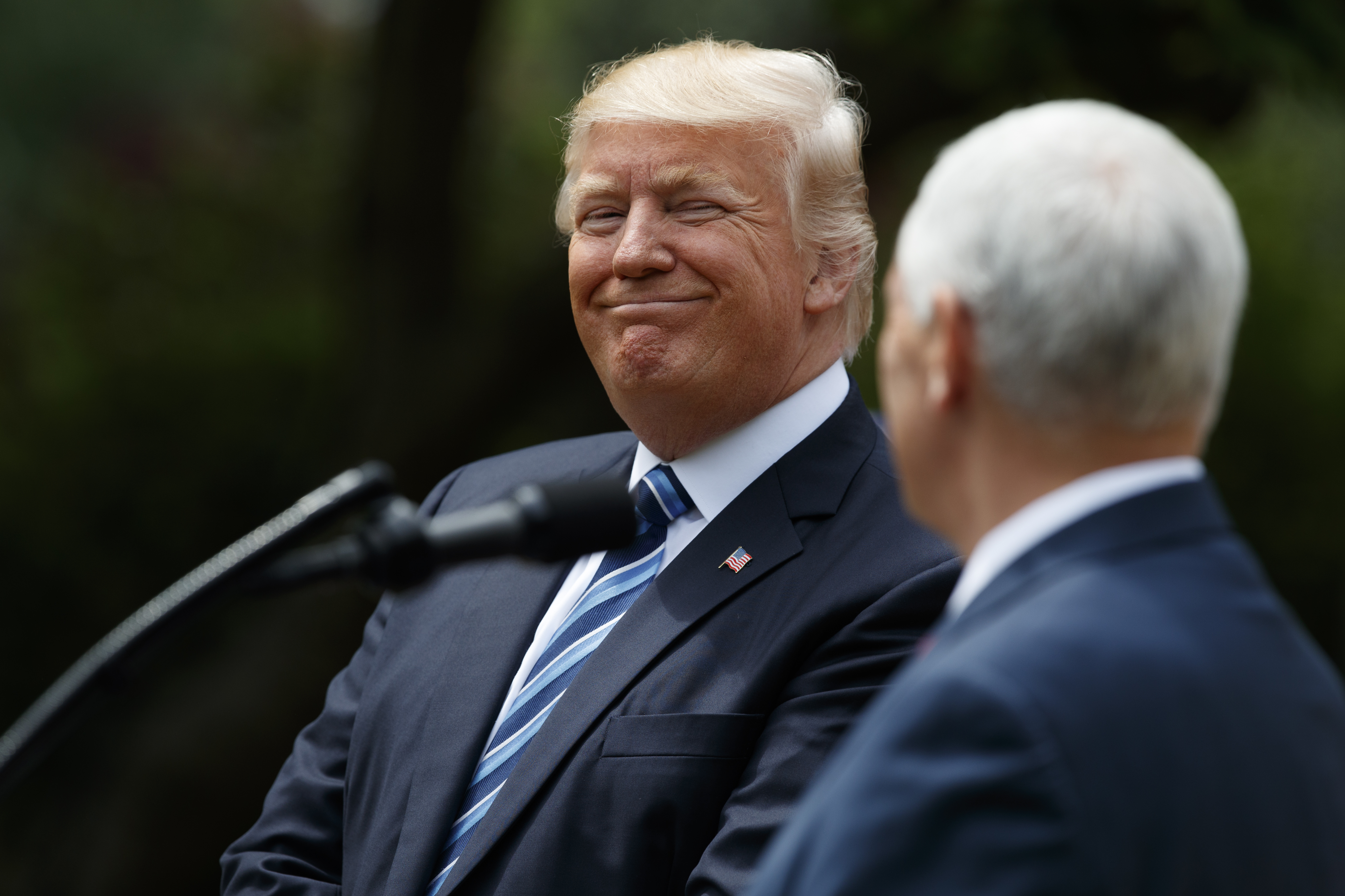 President Donald Trump smiles at Vice President Mike Pence before signing an executive order aimed at easing an IRS rule limiting political activity for churches. CREDIT: AP/Evan Vucci