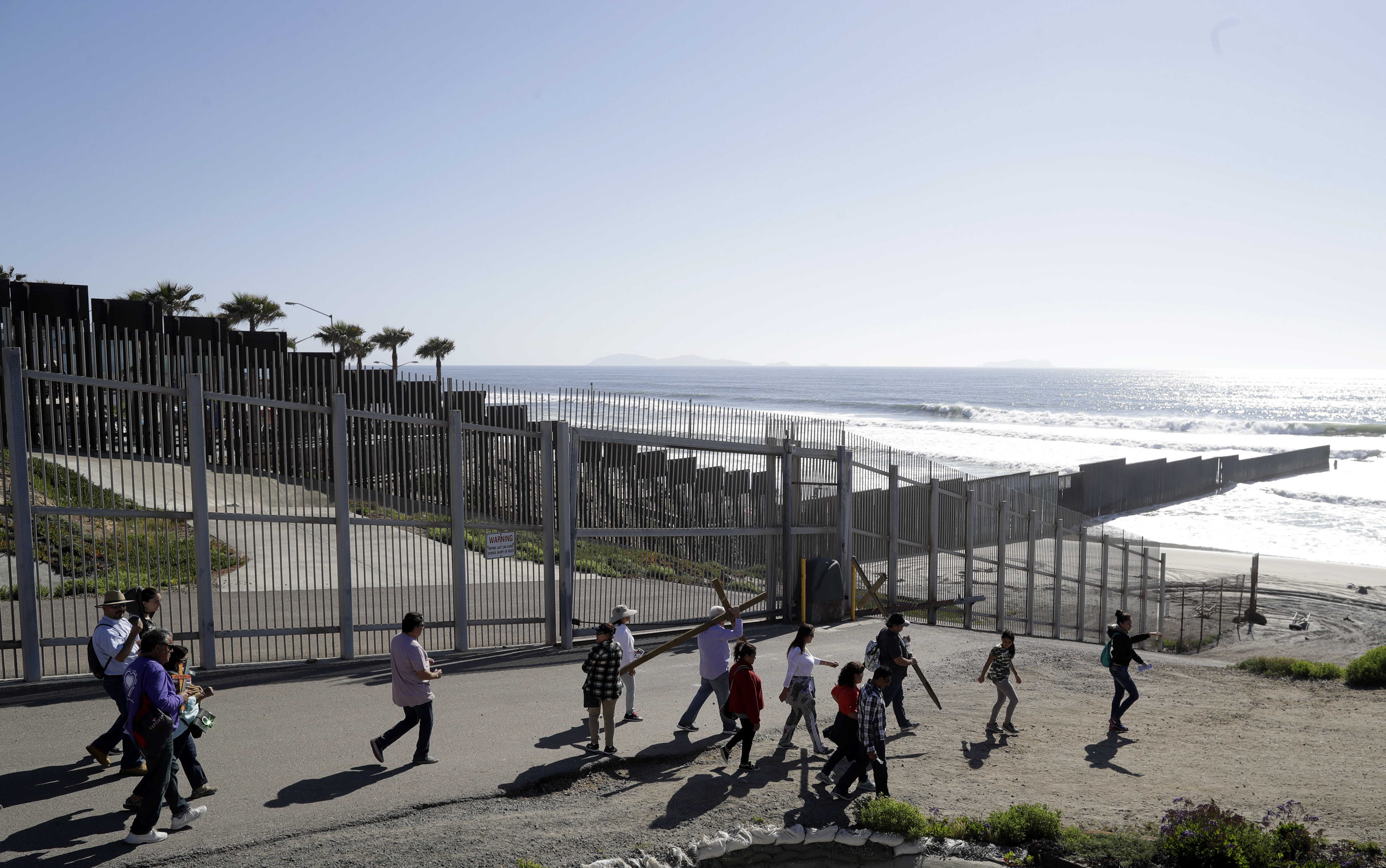A group from Los Angeles area churches carry crosses along the two fences that separate Tijuana, Mexico, behind, and San Diego. CREDIT: AP Photo/Gregory Bull