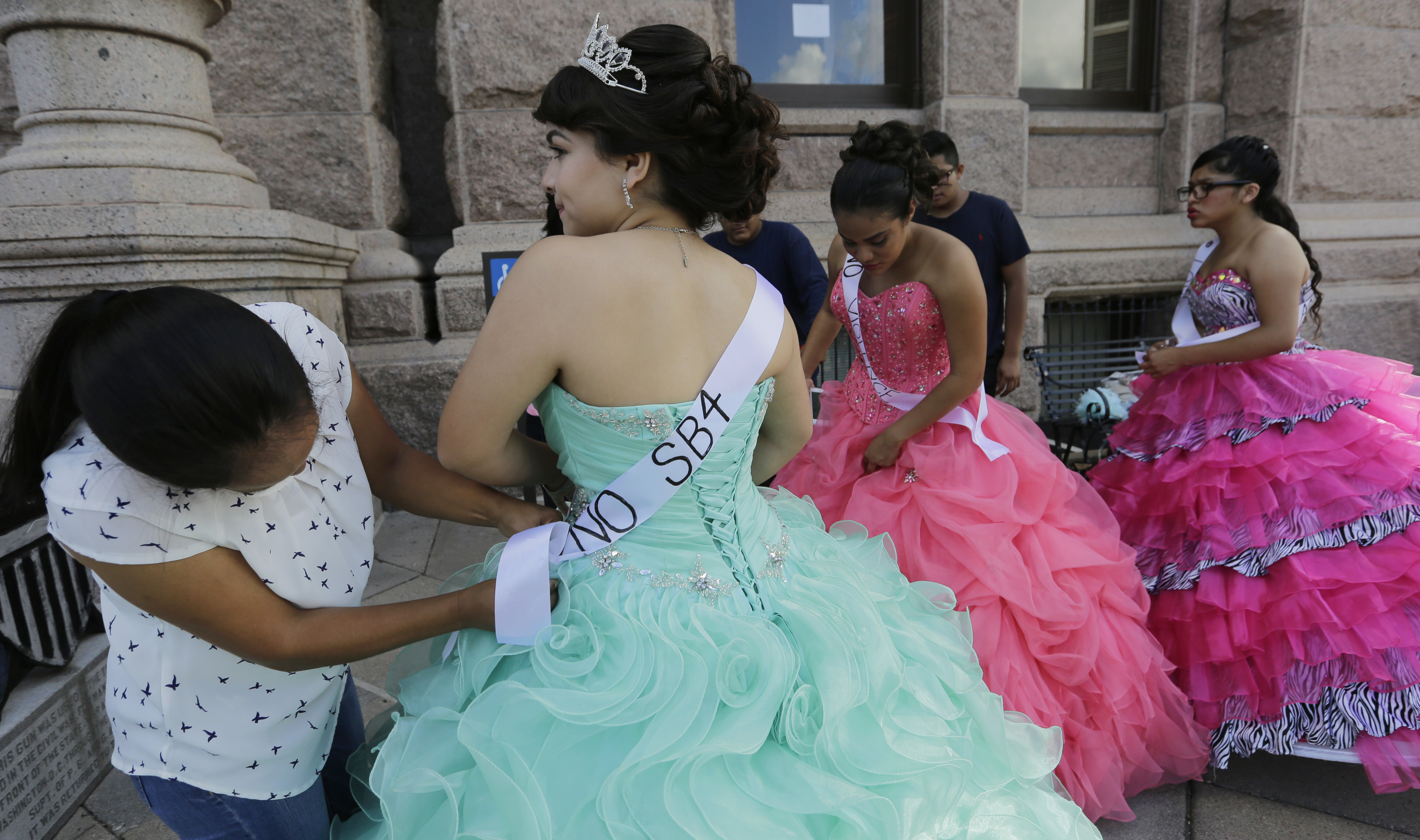 Dressed as Quinceaneras, Jennifer Ramirez, center, and others prepare to perform and protest SB4, an anti-"sanctuary cities" bill, at the Texas Capitol in Austin, Texas, July 19, 2017. CREDIT: AP Photo/Eric Gay