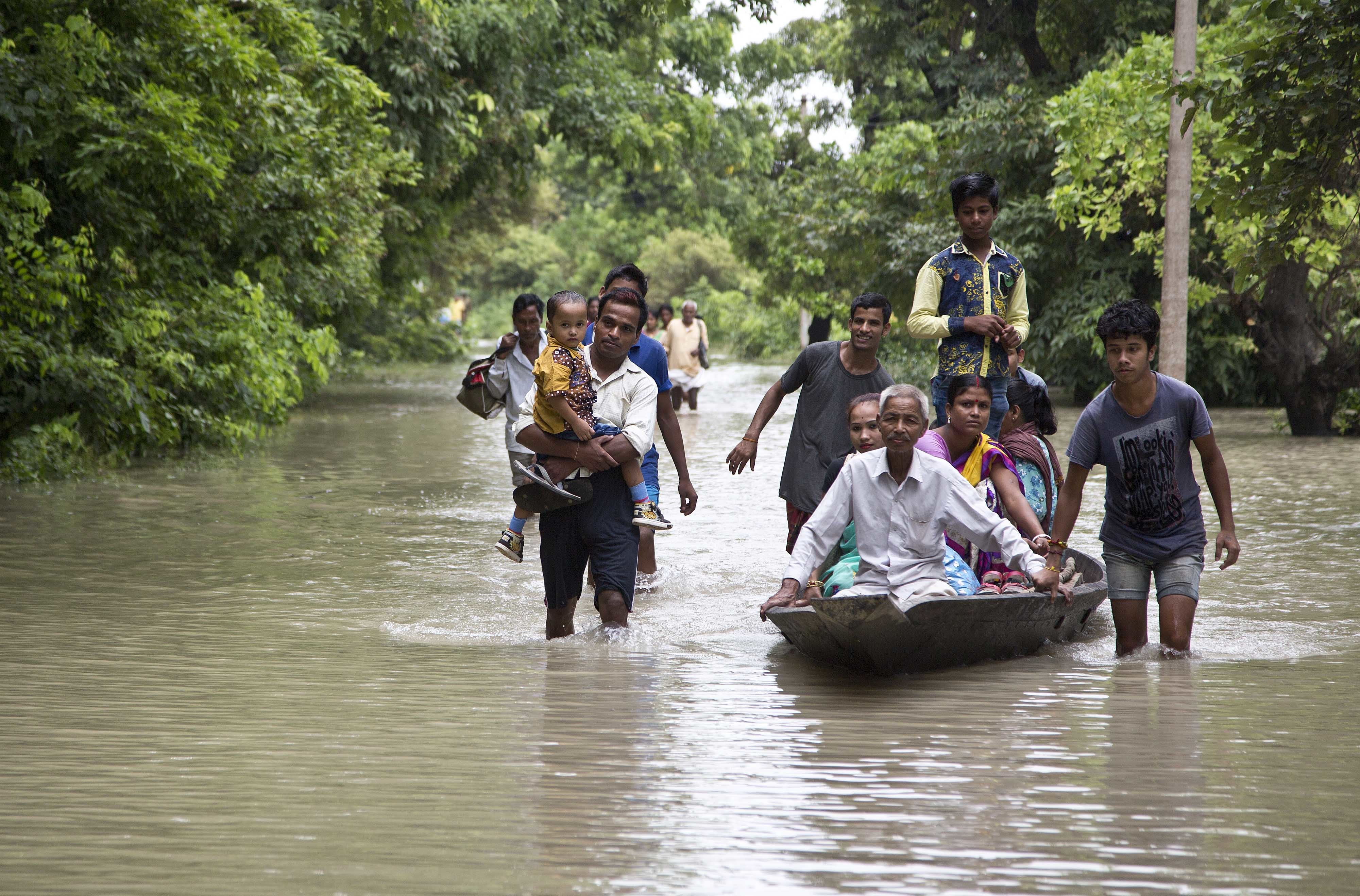 Commuters wade through flood waters on a road in Murkata village east of Gauhati, north eastern Assam state, India , Monday, Aug. 14, 2017. CREDIT: AP Photo/Anupam Nath