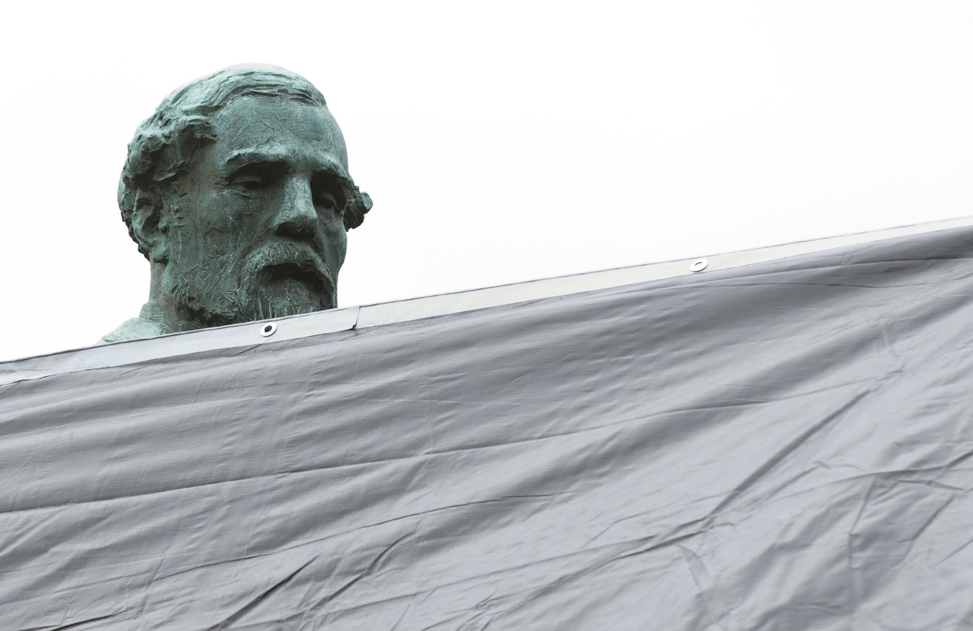 City workers drape a tarp over the statue of Confederate General Robert E. Lee in Emancipation park in Charlottesville, Virginia, on Wednesday. The move to cover the statues is intended to symbolize the city's mourning for Heather Heyer, killed while protesting a white nationalist rally earlier this month. CREDIT: AP Photo/Steve Helber