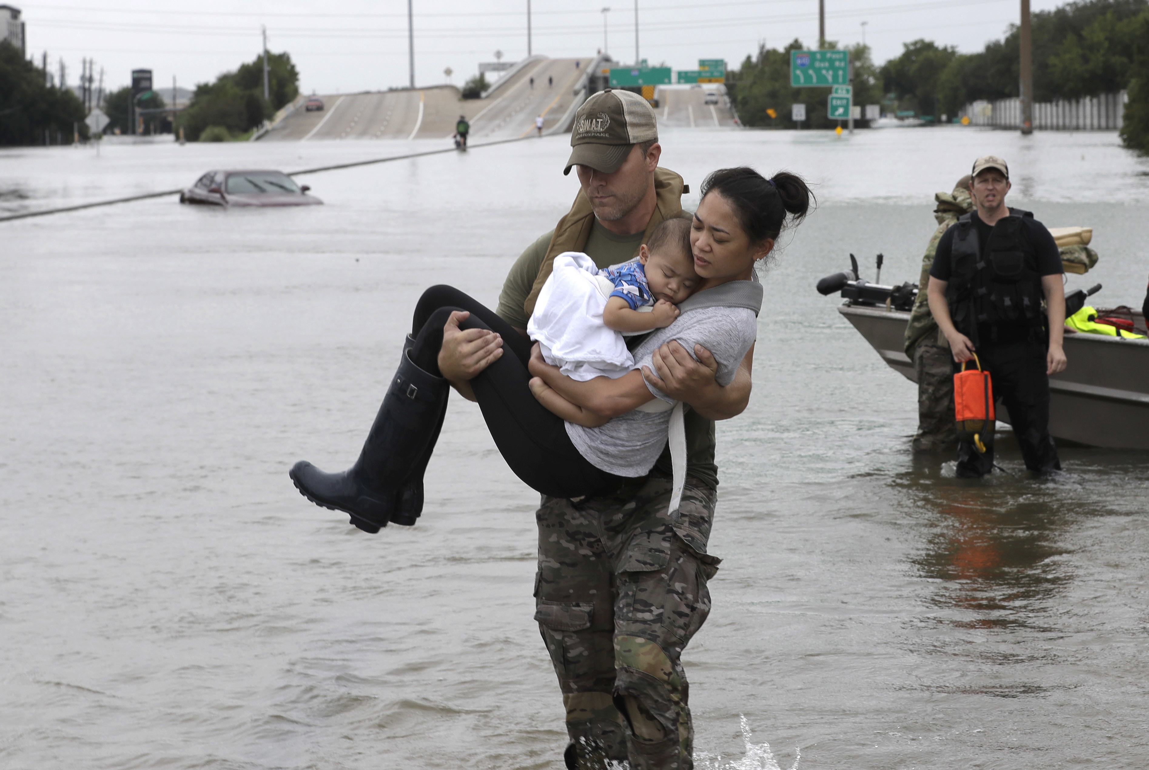 Houston Police SWAT officer Daryl Hudeck carries Catherine Pham and her 13-month-old son Aiden after rescuing them from their home surrounded by floodwaters from Tropical Storm Harvey Sunday, Aug. 27, 2017, in Houston. CREDIT: AP Photo/David J. Phillip