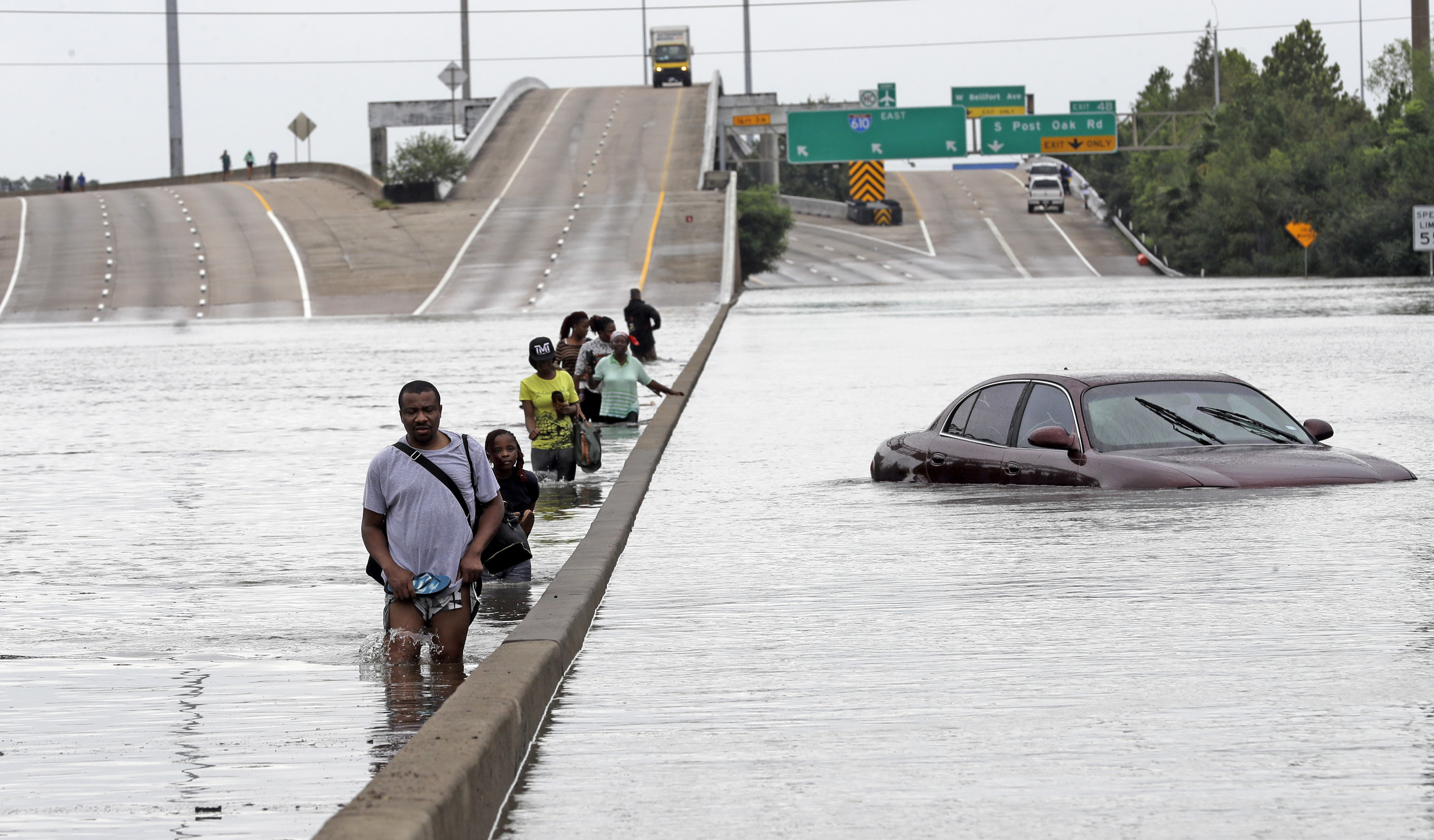 Evacuees wade down a flooded section of Interstate 610 as floodwaters from Tropical Storm Harvey rise Sunday, Aug. 27, 2017, in Houston. CREDIT: AP Photo/David J. Phillip