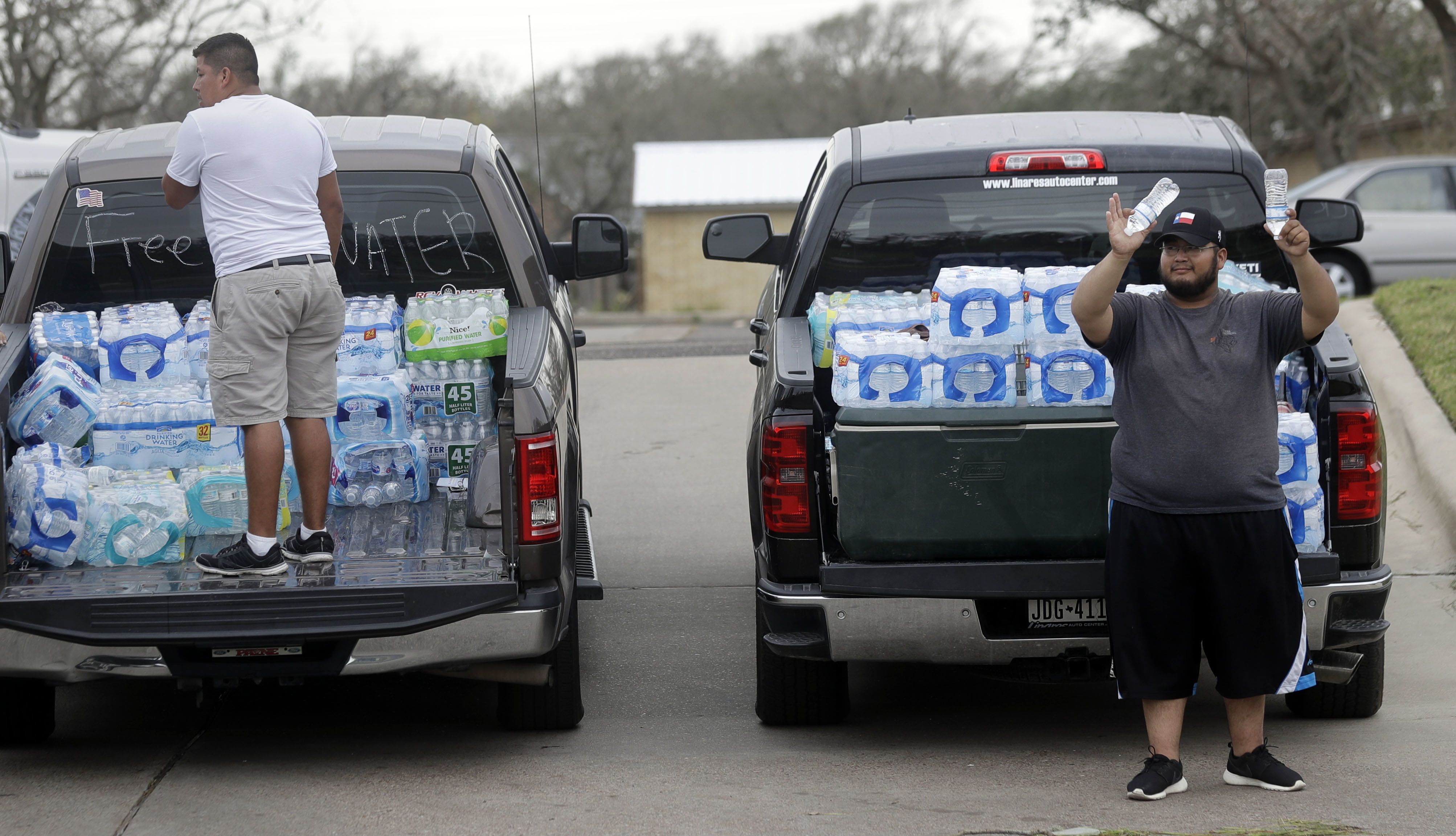 Miguel Juarez, right, offers free water to passing vehicles Sunday, Aug. 27, 2017, in Rockport, Texas. Juarez and others from the Texas Rio Grande Valley created a make-shift aid station for those in need following Hurricane Harvey. (Credit: AP Photo/Eric Gay)