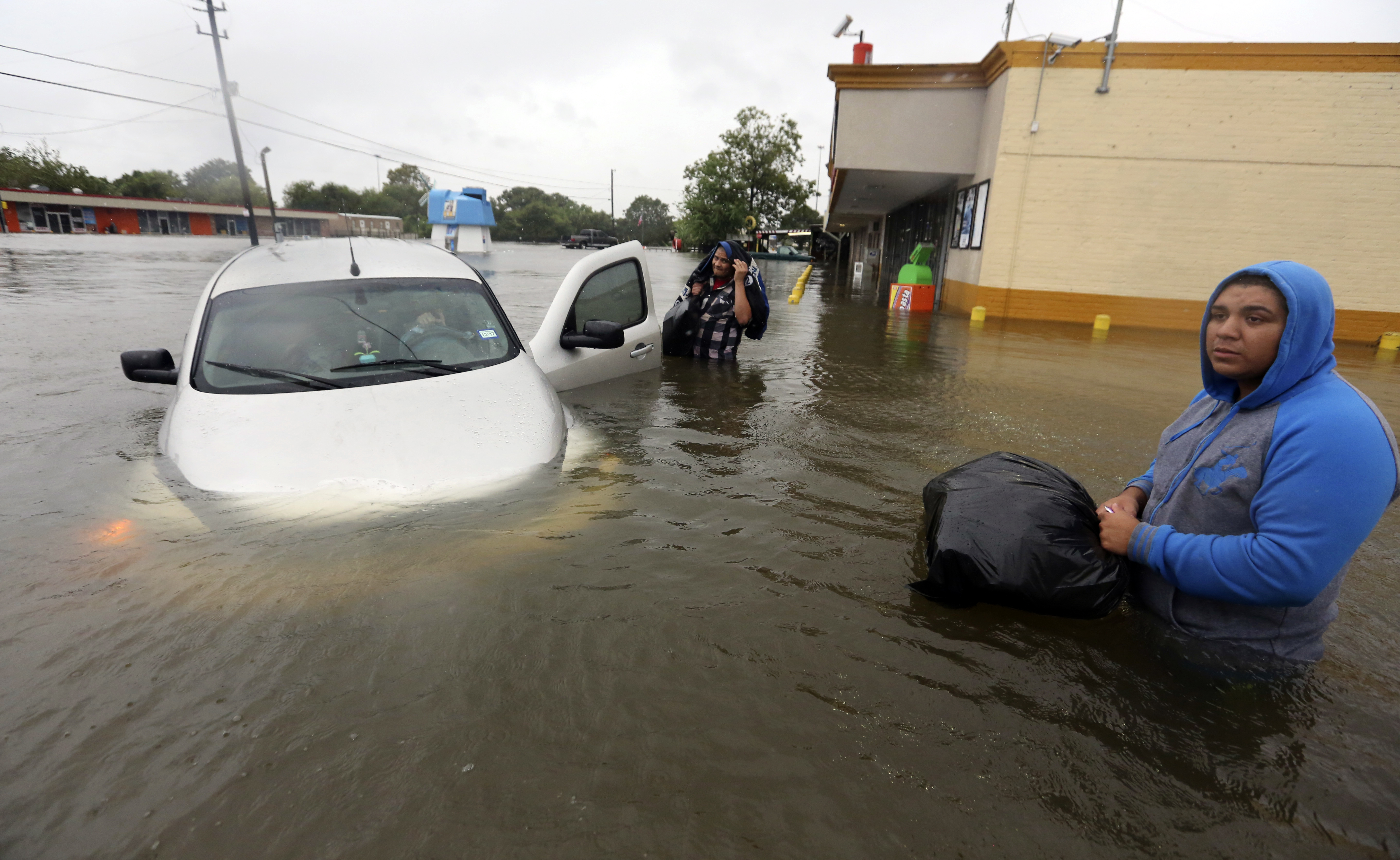 Conception Casa, center, and his friend Jose Martinez, right, check on Rhonda Worthington after her car became stuck in rising floodwaters from Tropical Storm Harvey in Houston, Texas. CREDIT: AP Photo/LM Otero