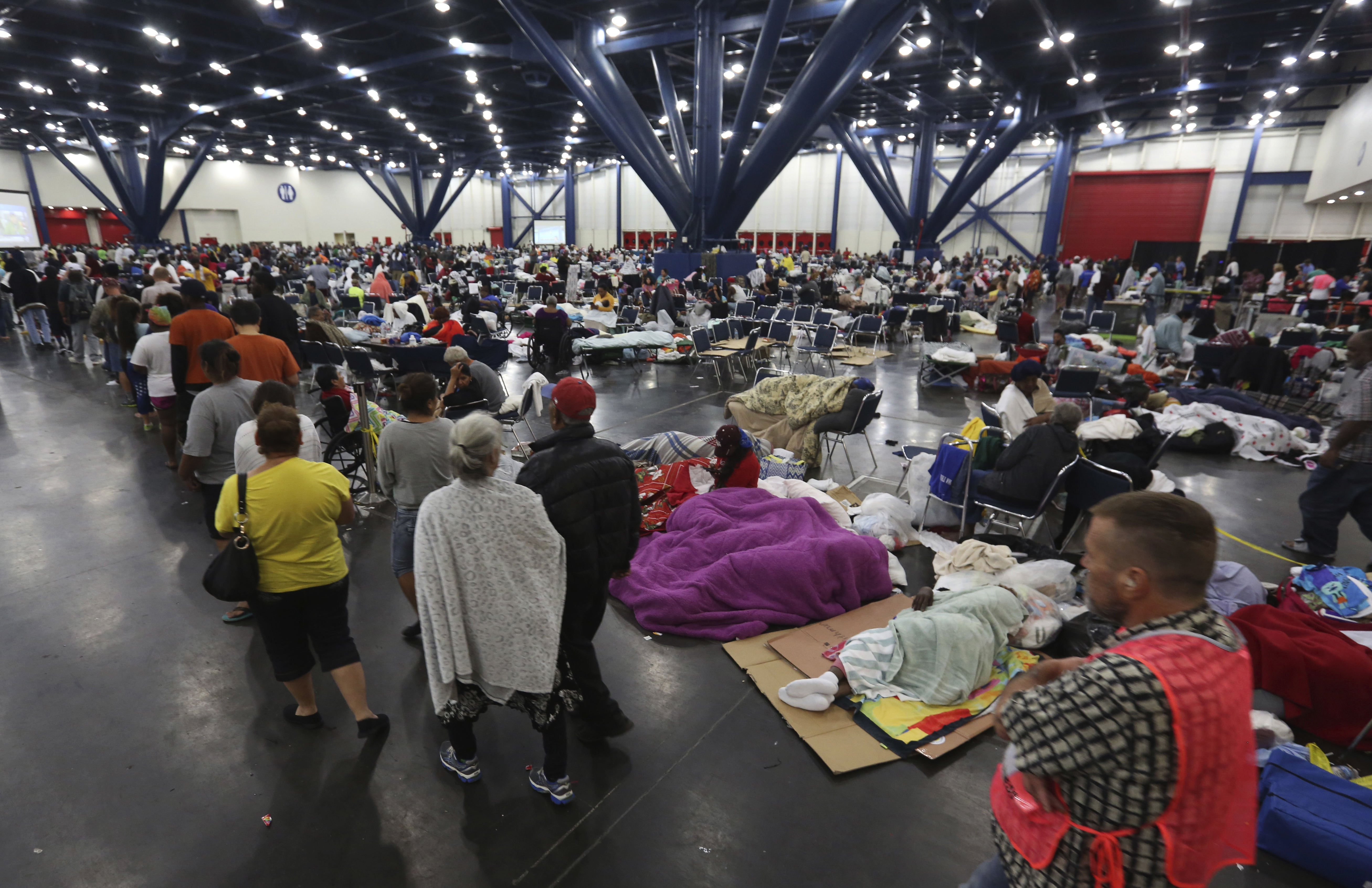 People line up for food as others rest at the George R. Brown Convention Center that has been set up as a shelter for evacuees escaping the floodwaters from Tropical Storm Harvey in Houston, Texas, Tuesday, Aug. 29, 2017. CREDIT: AP Photo/LM Otero