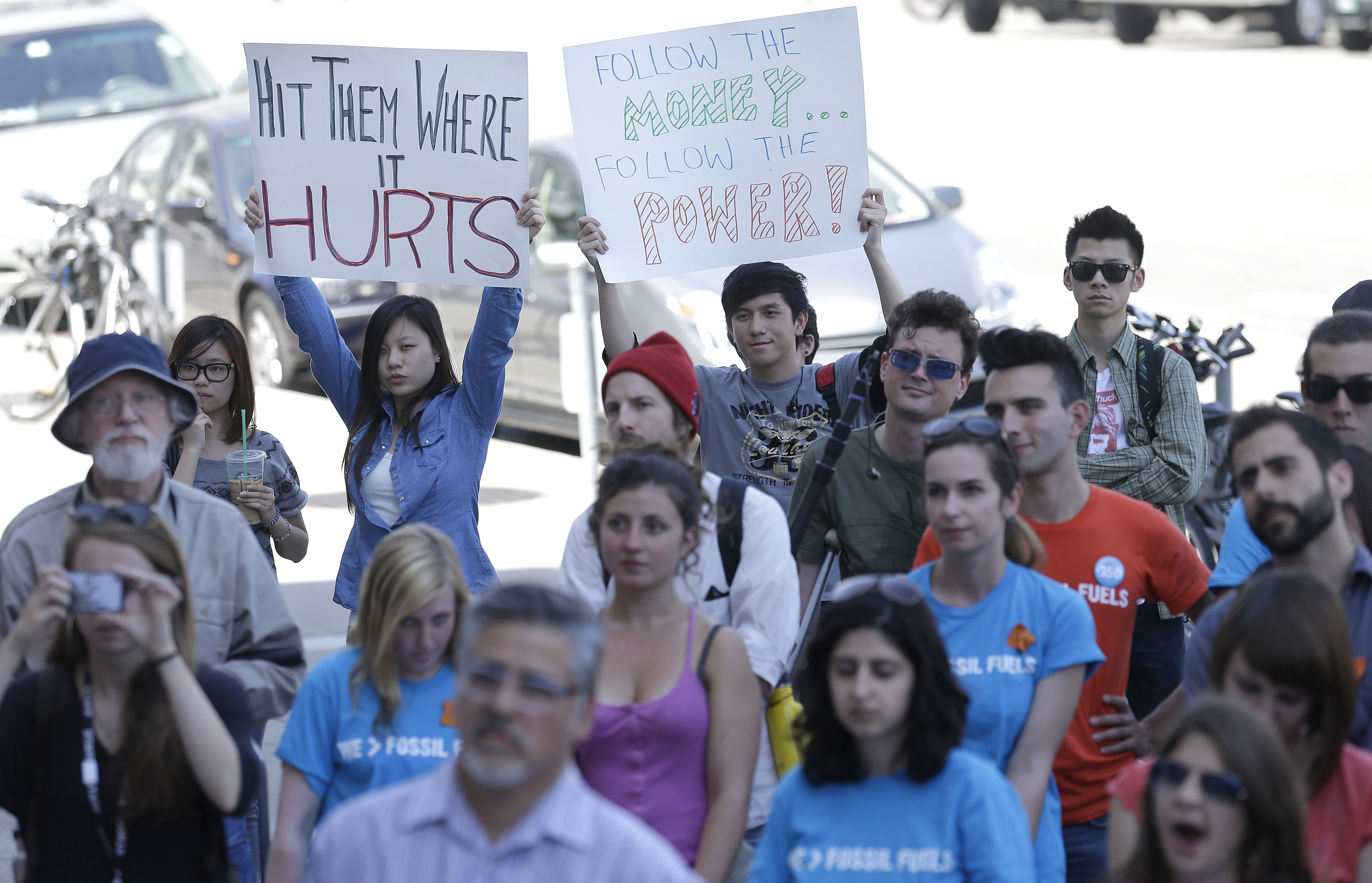 College students and supporters hold up signs at a rally to support fossil fuel divestment outside of City Hall in San Francisco, Thursday, May 2, 2013. In an effort to slow the pace of climate change, students at more than 200 colleges are asking their schools to stop investing in fossil fuel companies. (AP Photo/Jeff Chiu)