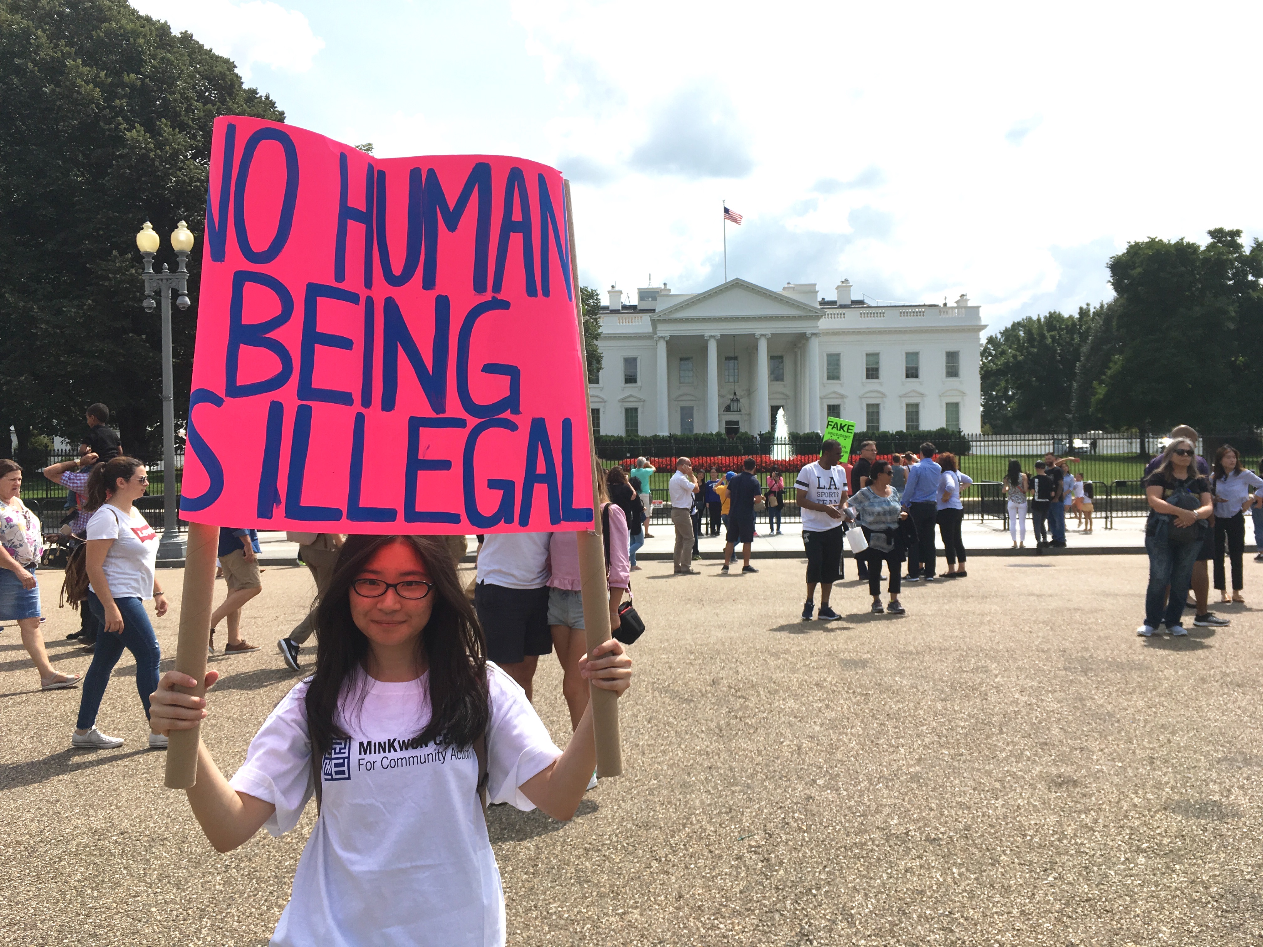 Yoojin Kim, a DACA beneficiary, holds a sign reading "No human being is illegal" during a rally at the White House on August 28, 2017. CREDIT: Esther Lee/ ThinkProgress