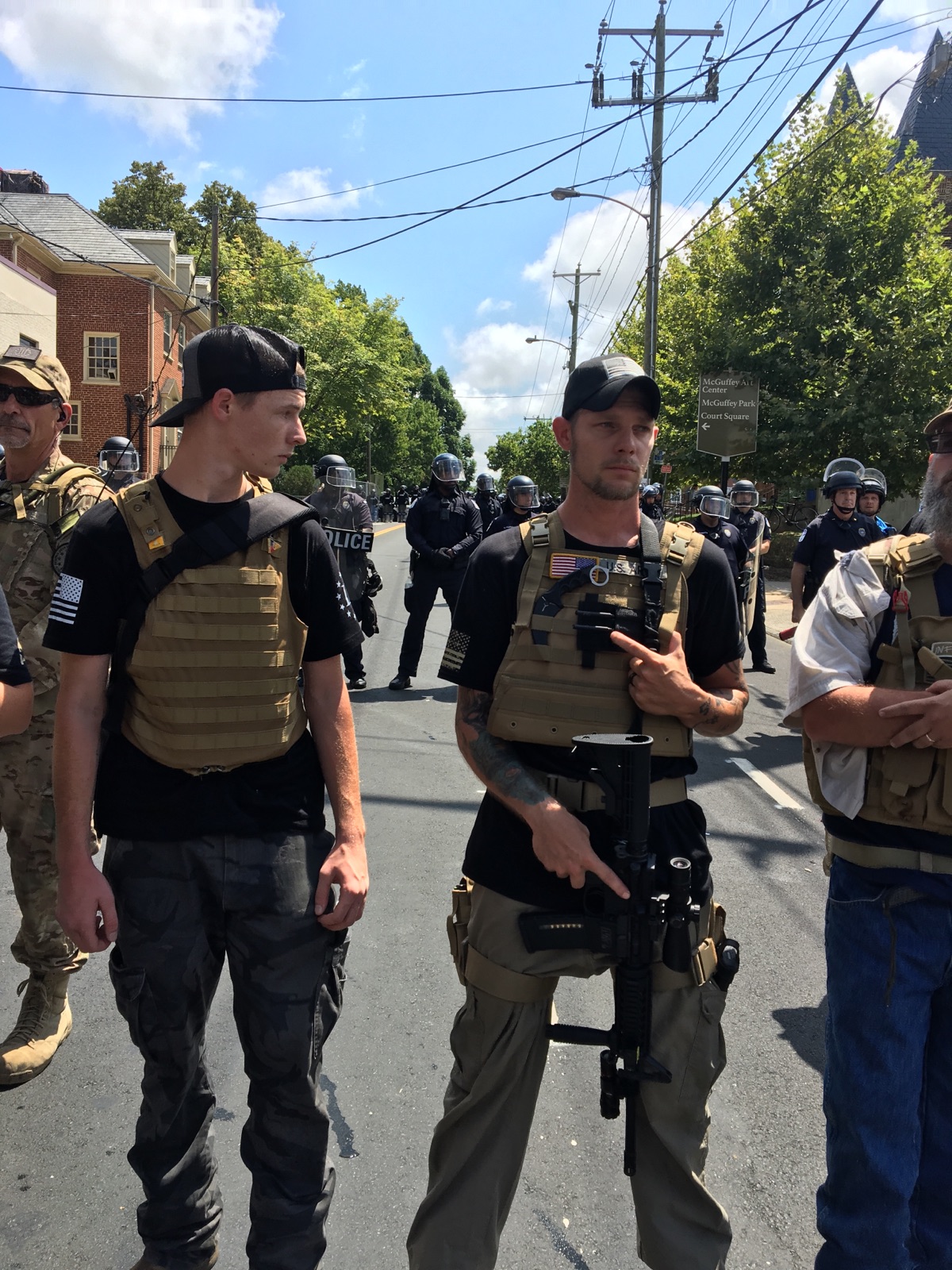 Armed militiamen stand in front of riot police after Saturday's white supremacist rally was deemed an unlawful gathering in Charlottesville, VA. CREDIT: ThinkProgress/Joshua Eaton