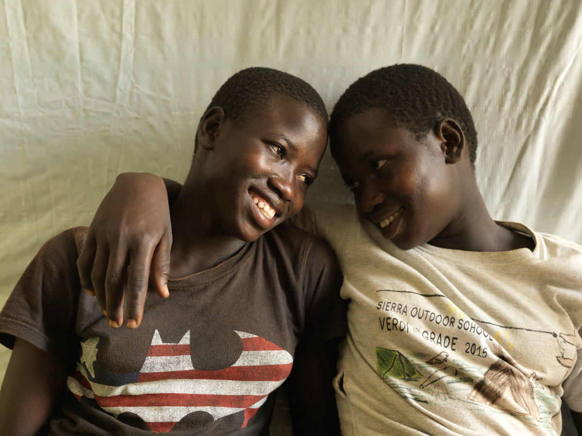 Tabu Sunday (left), the symbolically named one millionth South Sudanese refugee to arrive in Uganda, relaxes with her twin sister Rena in their shelter at the Imvepi settlement. CREDIT: UNHCR/Peter Caton