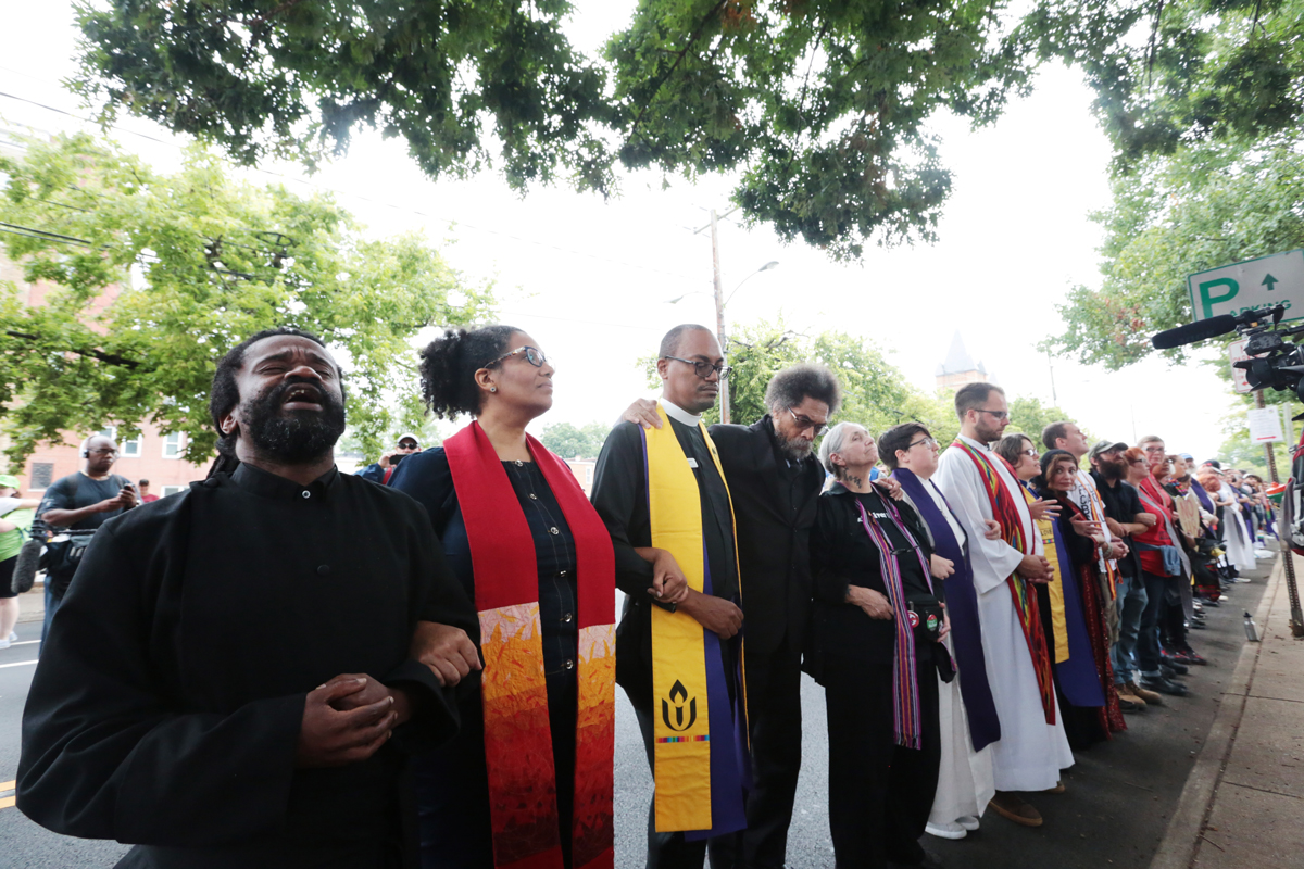 From left: Rev. Osagyefo Sekou, Lisa Sharon Harper, Rev. Carlton Smith, Cornel West, and others (including Seth Wispelwey wearing a white robe and red stole) protesting white supremacy in Charlottesville. CREDIT: Heather Wilson, @aNomadPhotog / Dust & Light Photo