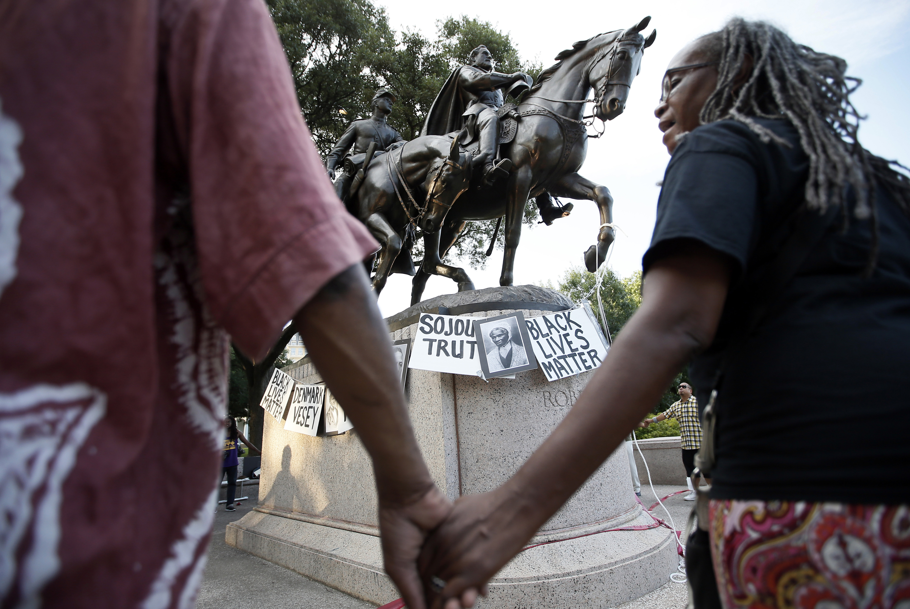 In this June 30, 2015, file photo, activists gather around the Confederate Army Gen. Robert E. Lee statute at Lee Park chanting the names of Civil War era activists in Dallas. Gen. Robert E. Lee was vilified during the Civil War only to become a heroic symbol of "The Lost Cause" and eventually a racist icon. Historians say his transformation, at the center of the recent violence in Charlottesville, Va., reflects the changing moods in the United States around race, mythology and national reconciliation. (AP Photo/Tony Gutierrez, File)