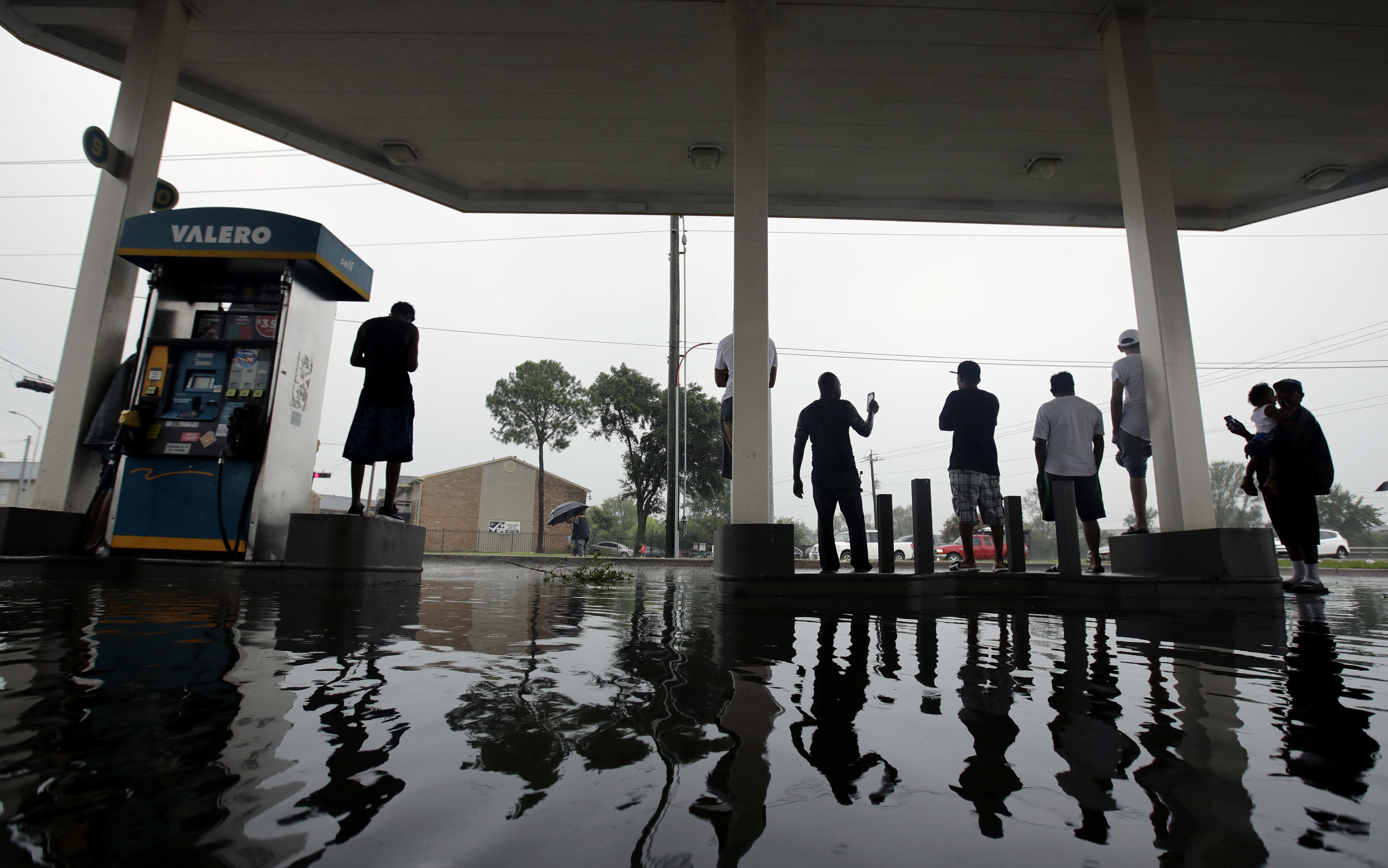People watch heavy rain from a flooded gas station caused by Tropical Storm Harvey on Sunday, Aug. 27, 2017, in Houston. CREDIT: AP Photo/Charlie Riedel