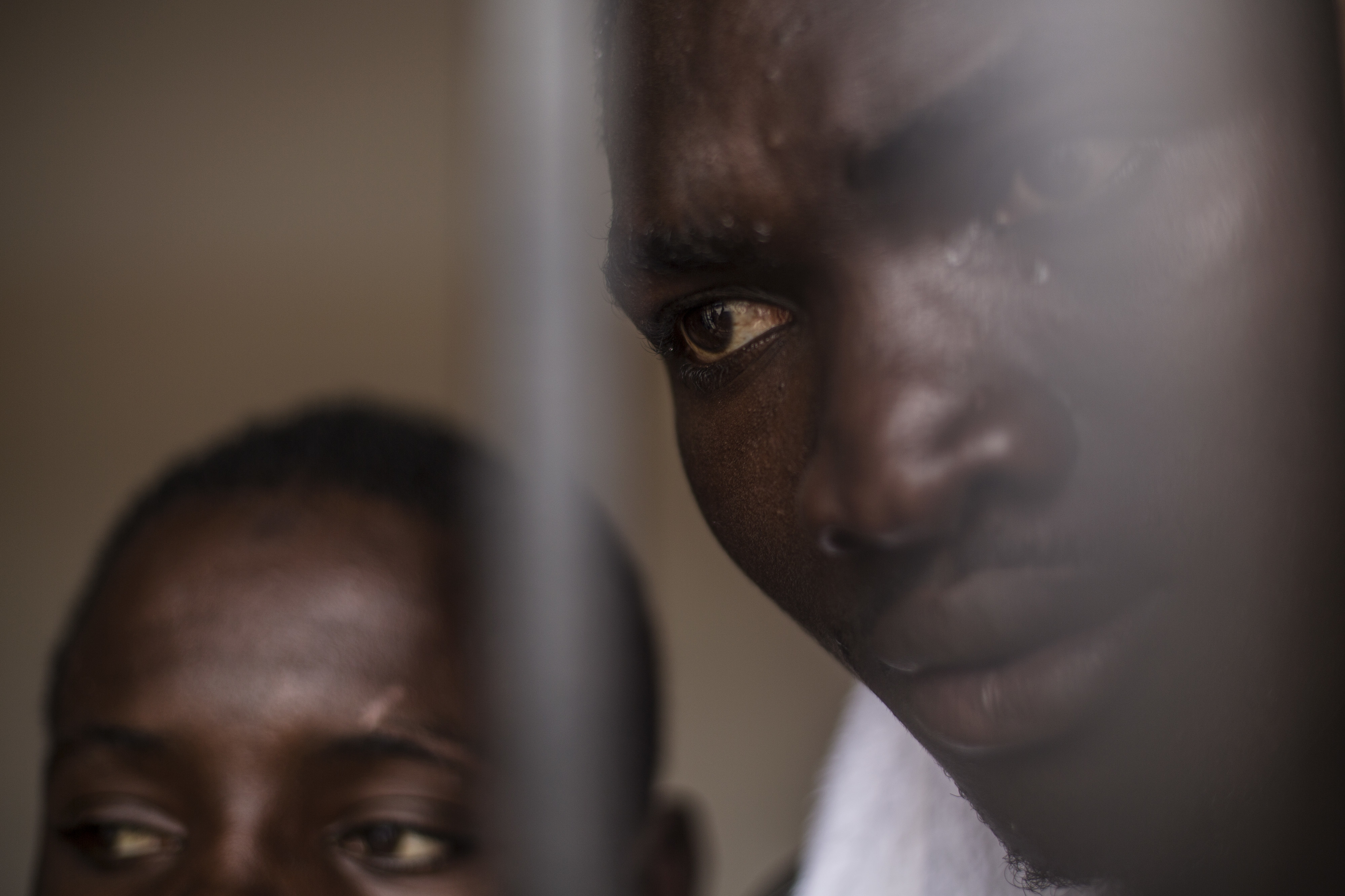 Migrants are seen behind the bars of a window at a detention center for migrants, in the village of Karareem, around 50 km from Misrata, Libya. CREDIT: Manu Brabo/AP Photo
