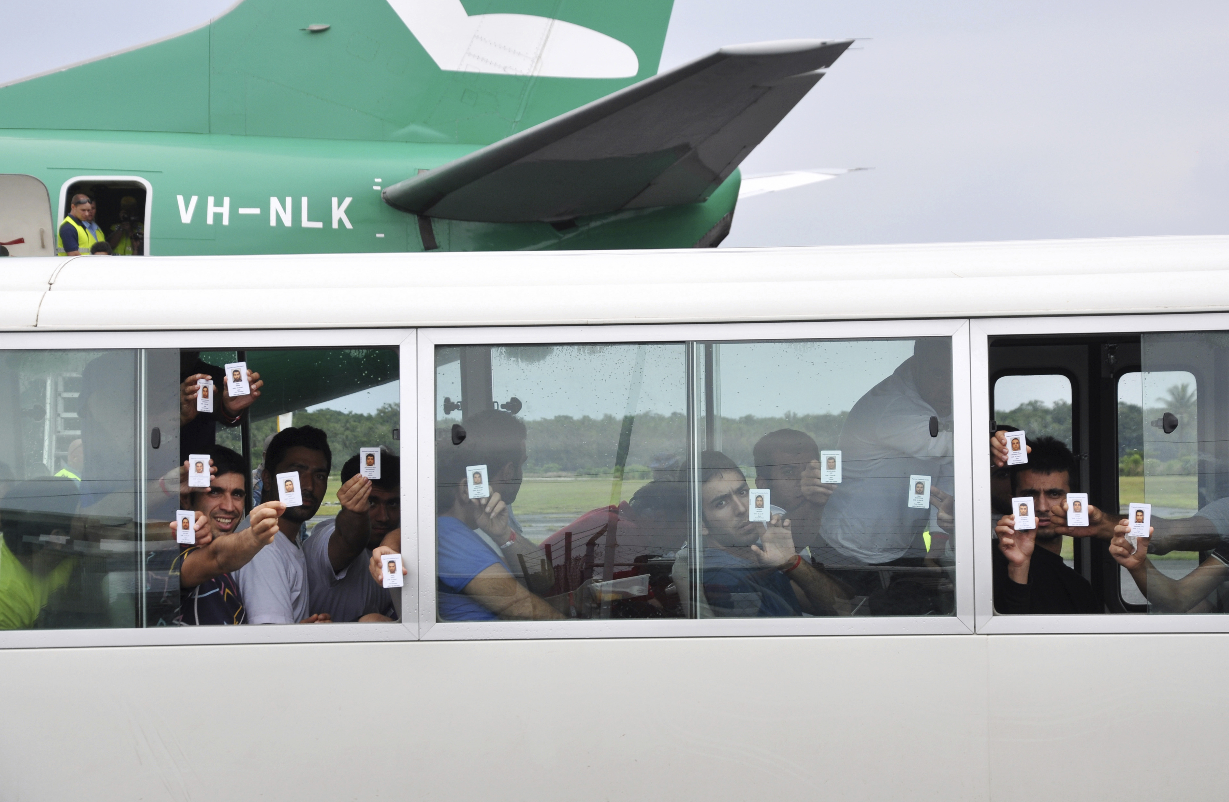 A group of asylum seekers hold up their identity after landing in Manus Island, Papua New Guinea. CREDIT: Eoin Blackwell/AAP Image, via AP
