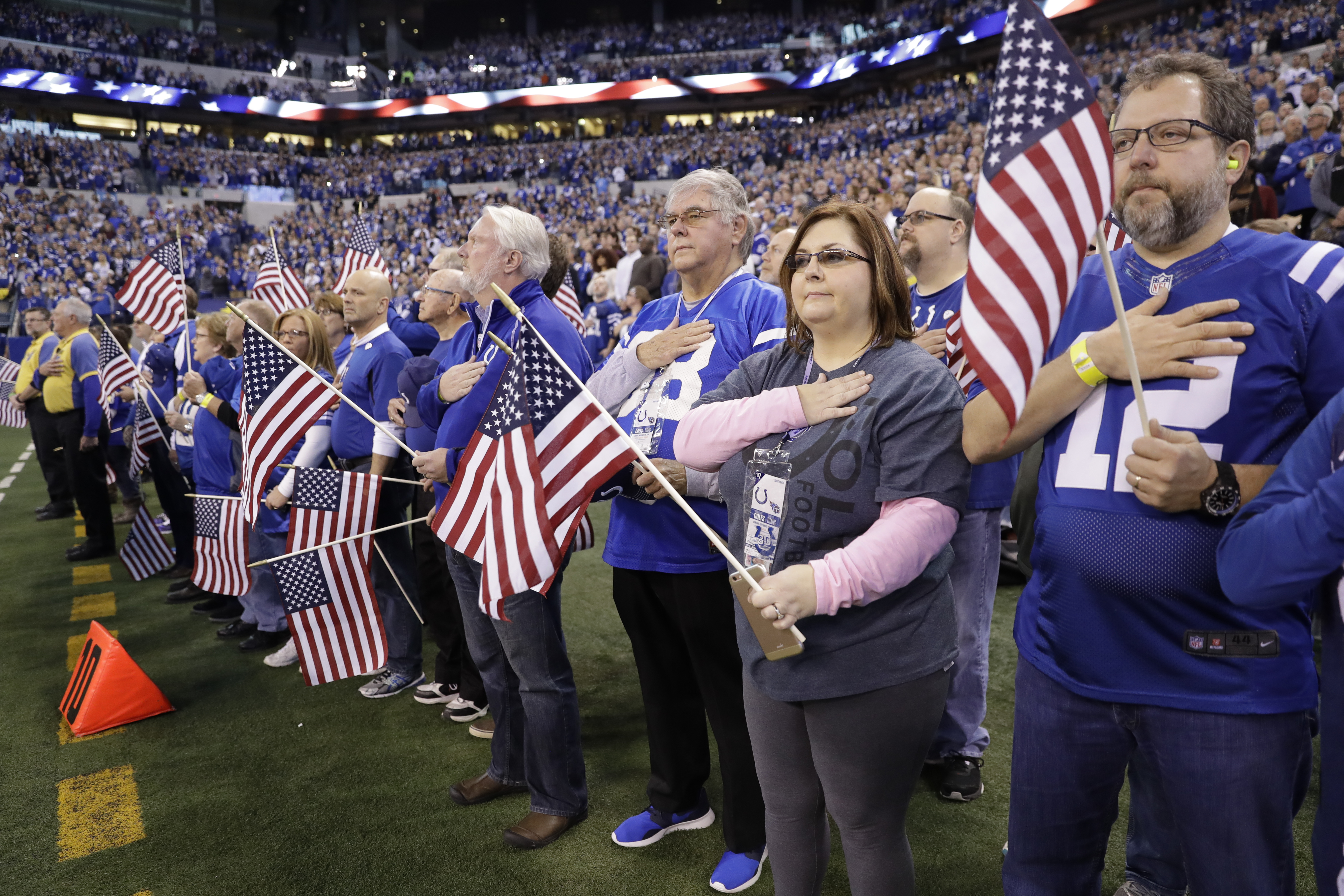 Family members of veterans wave an American flag before an NFL football game between the Tennessee Titans and the Indianapolis Colts. (Credit: AP Photo/Darron Cummings)