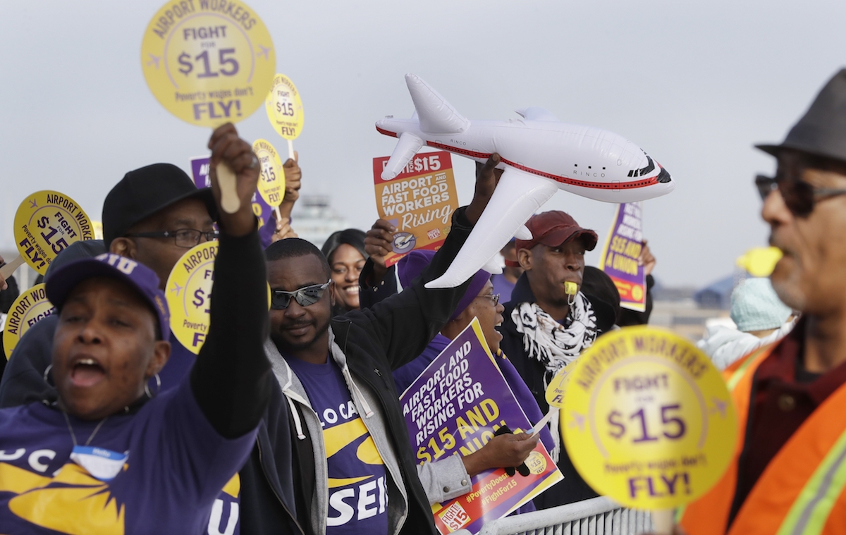 SEIU Local 1 union members protest for an increase in the minimum wage, Tuesday, Nov. 29, 2016, at the Detroit Metropolitan Airport in Romulus, Mich. Fast-food restaurant and airport workers, as well as home and child-care workers rallied in cities including Chicago, Detroit, Houston, Los Angeles, Minneapolis and New York on Tuesday morning. In many cities the protesters blocked busy intersections. (AP Photo/Carlos Osorio)