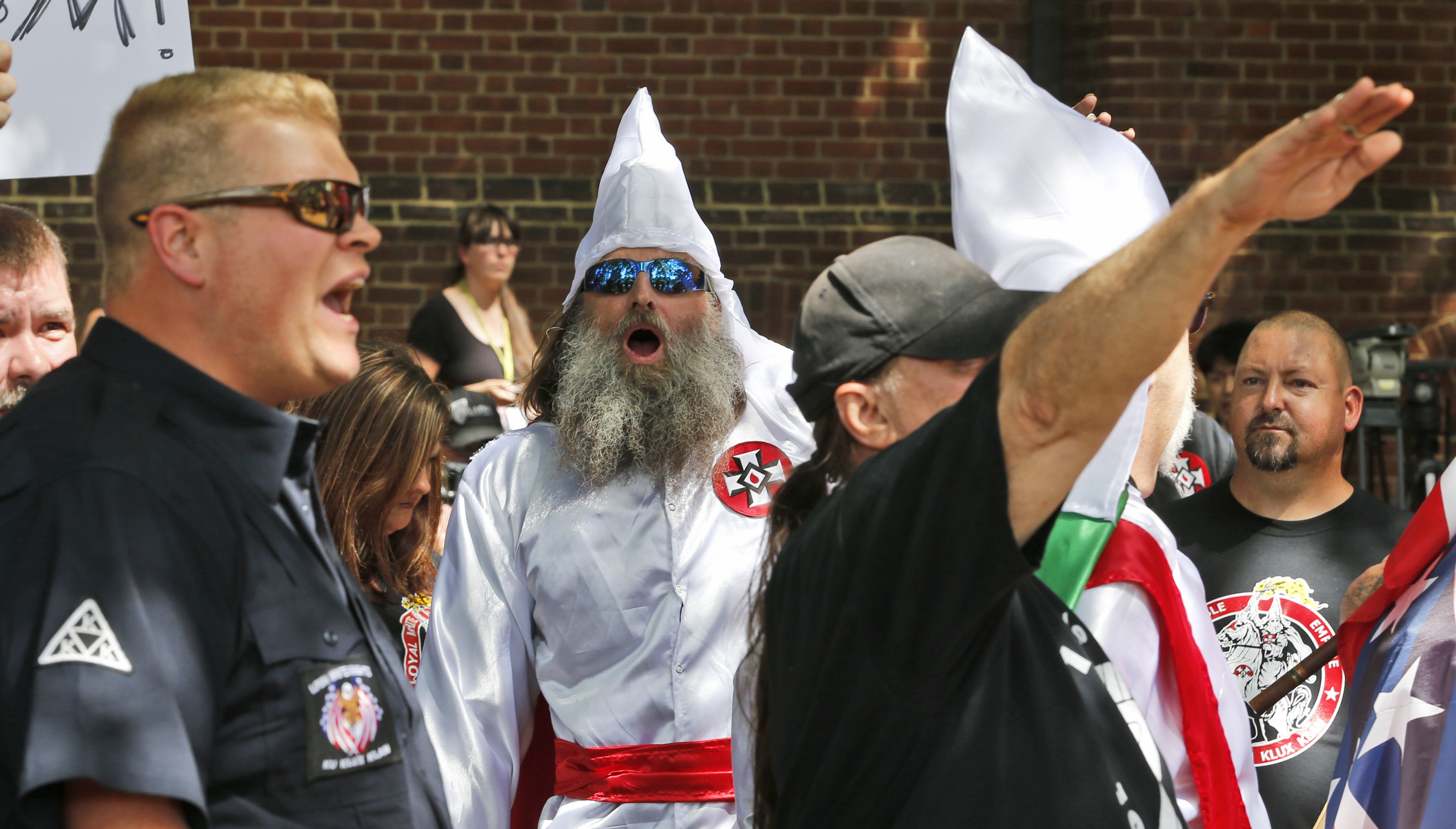 Members of the KKK are escorted by police past a large group of protesters during a KKK rally Saturday, July 8, 2017, in Charlottesville, Va. CREDIT: AP Photo/Steve Helber