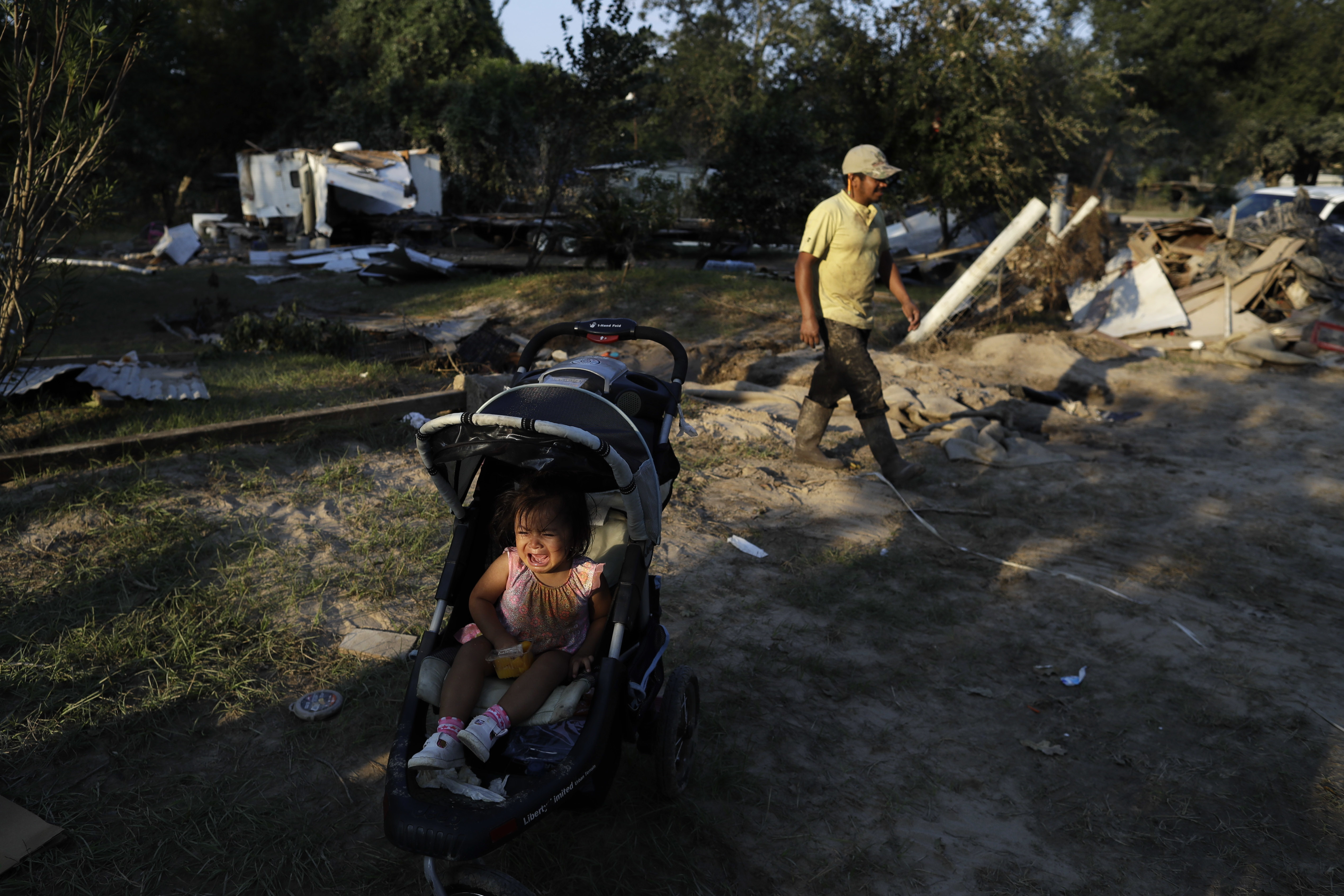 Melisa Vasquez cries in a stroller as her father Ervin Vasquez digs out from the destruction left when floodwaters from Harvey swept through their mobile home in Crosby, Texas. CREDIT: AP Photo/Gregory Bull