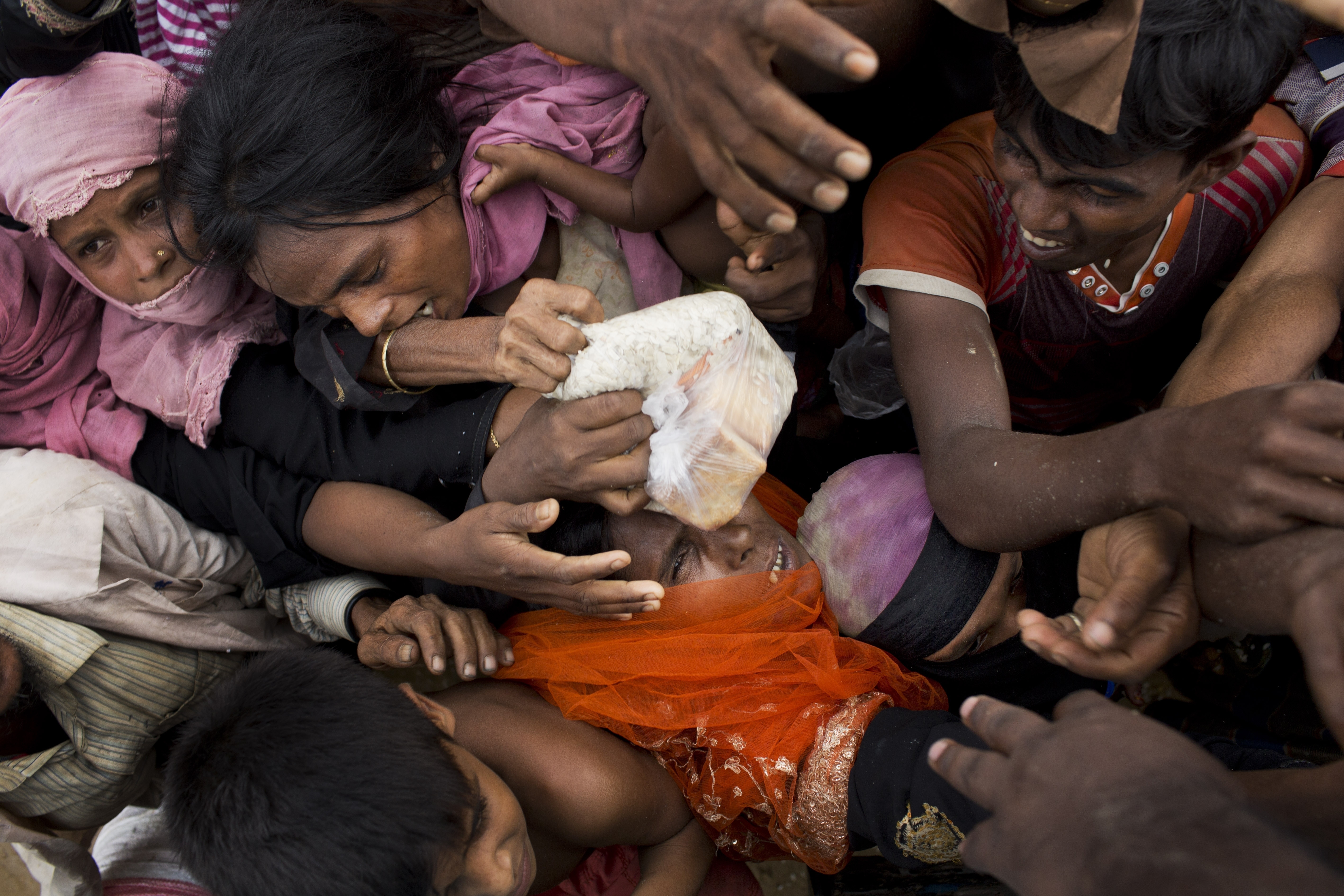 Newly arrived Rohingya from Myanmar, scuffle for puffed rice food rations donated by local volunteers in Kutupalong, Bangladesh. With Rohingya refugees still crossing the border in large numbers, those packed into camps and settlements in Bangladesh are desperate for dwindling basic supplies. Fights are erupting over food and water. CREDIT: Bernat Armangue/AP Photo