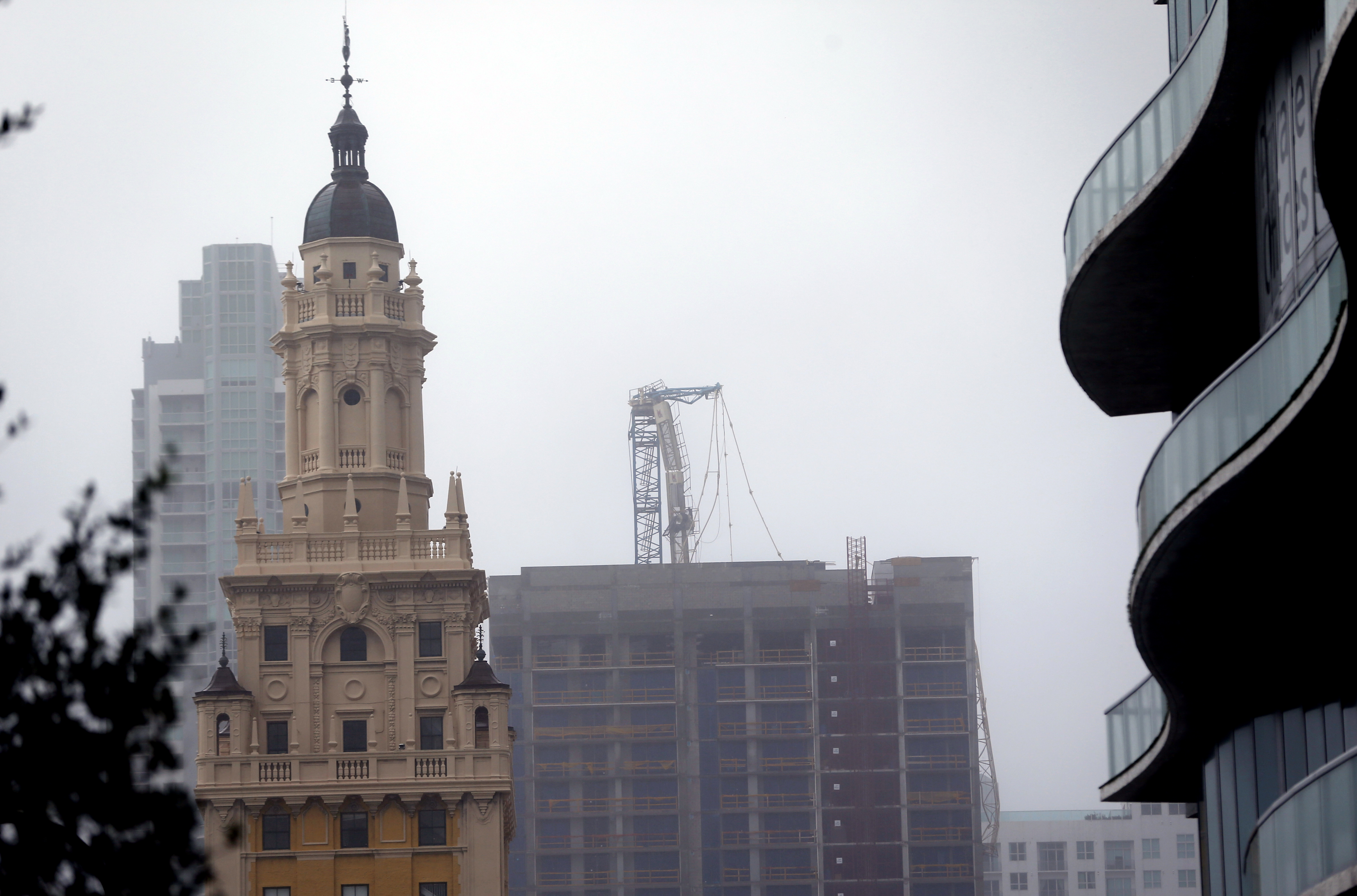 A crane atop a building under construction in downtown, center, collapsed as Hurricane Irma passed by, Sunday, Sept. 10, 2017, in Miami. The crane collapsed in a bayfront area filled with hotels and high-rise condo and office buildings, near AmericanAirlines Arena, according to a tweet from the City of Miami. CREDIT: AP Photo/Wilfredo Lee