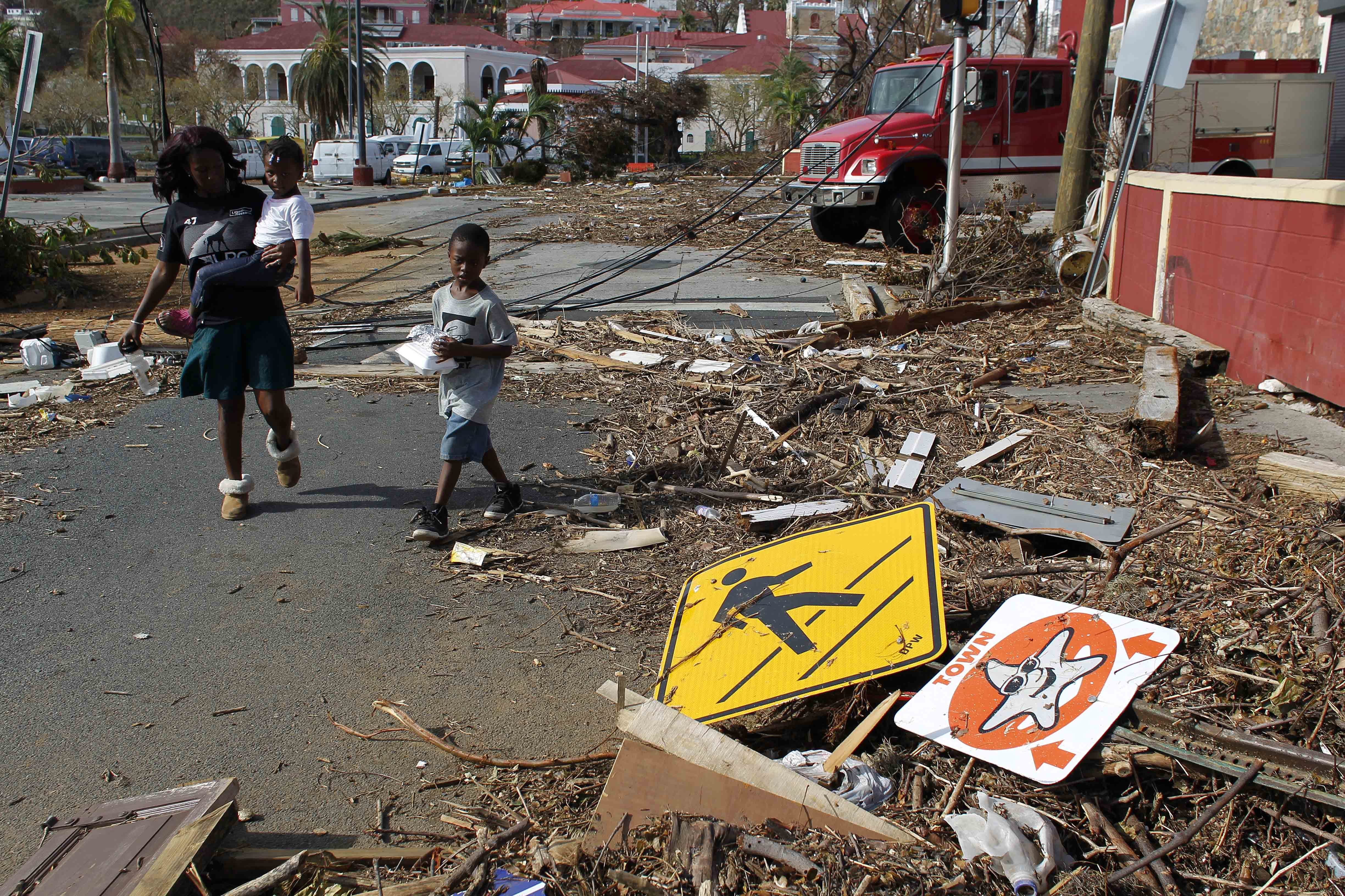 A woman with her two children walk past debris left by Hurricane Irma in Charlotte Amalie, St. Thomas, U.S. Virgin Islands, Sunday, Sept. 10, 2017. CREDIT: AP Photo/Ricardo Arduengo