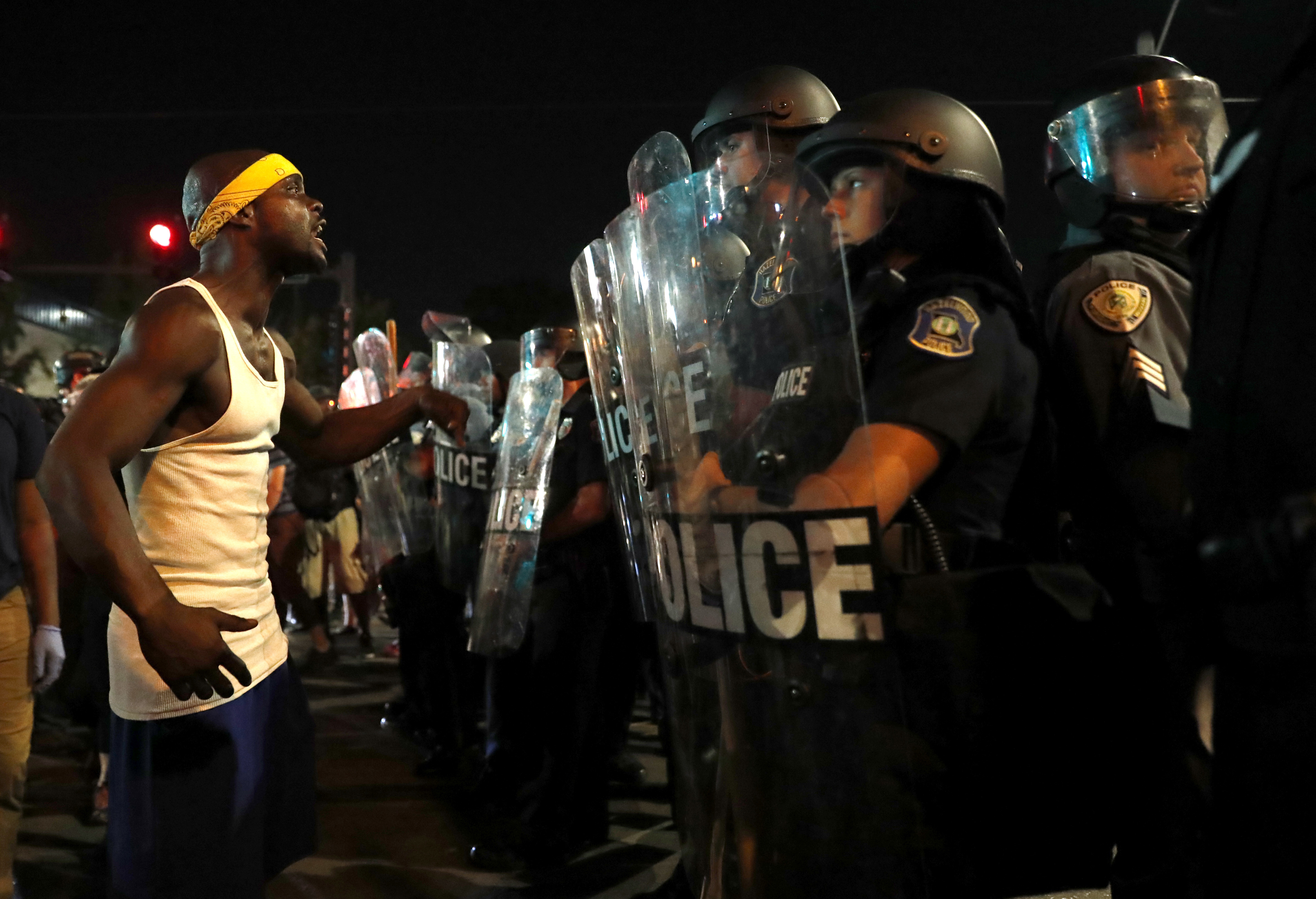 A man yells at police in riot gear just before a crowd turned violent Saturday, Sept. 16, 2017, in University City, Mo. Earlier, protesters marched peacefully in response to a not guilty verdict in the trial of former St. Louis police officer Jason Stockley. CREDIT: AP Photo/Jeff Roberson