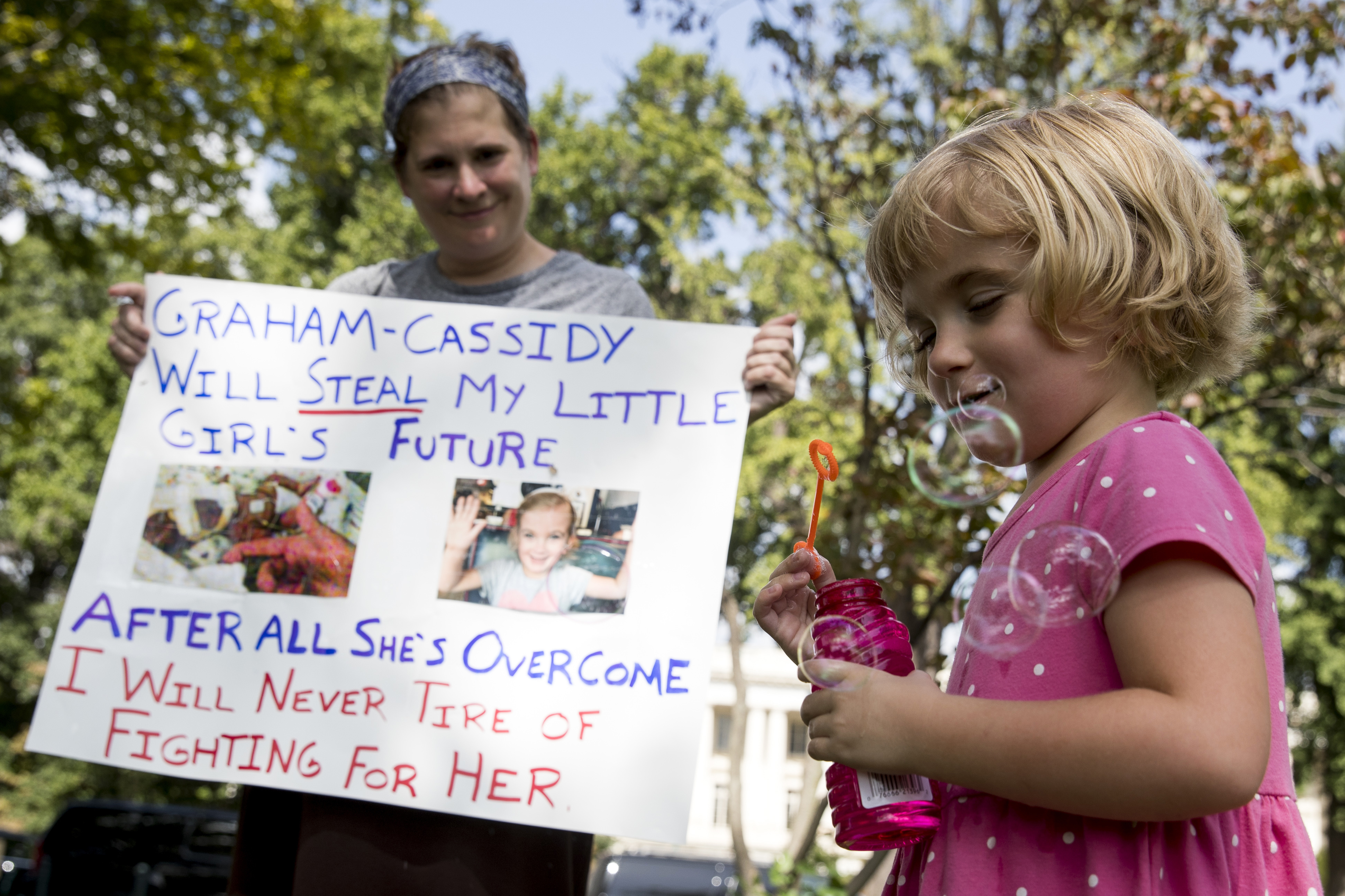 Rebecca Wood of Charlottesville, Va., watches as he daughter, Charlie, 5, blows bubbles at a rally of health care advocates, grassroots activists, and others outside the Capitol in Washington, Tuesday, Sept. 19, 2017. Charlie had medical complications and was born prematurely at 26 weeks. Senate Republicans begin another push to repeal the Affordable Care Act with the Graham-Cassidy proposal. (AP Photo/Andrew Harnik)