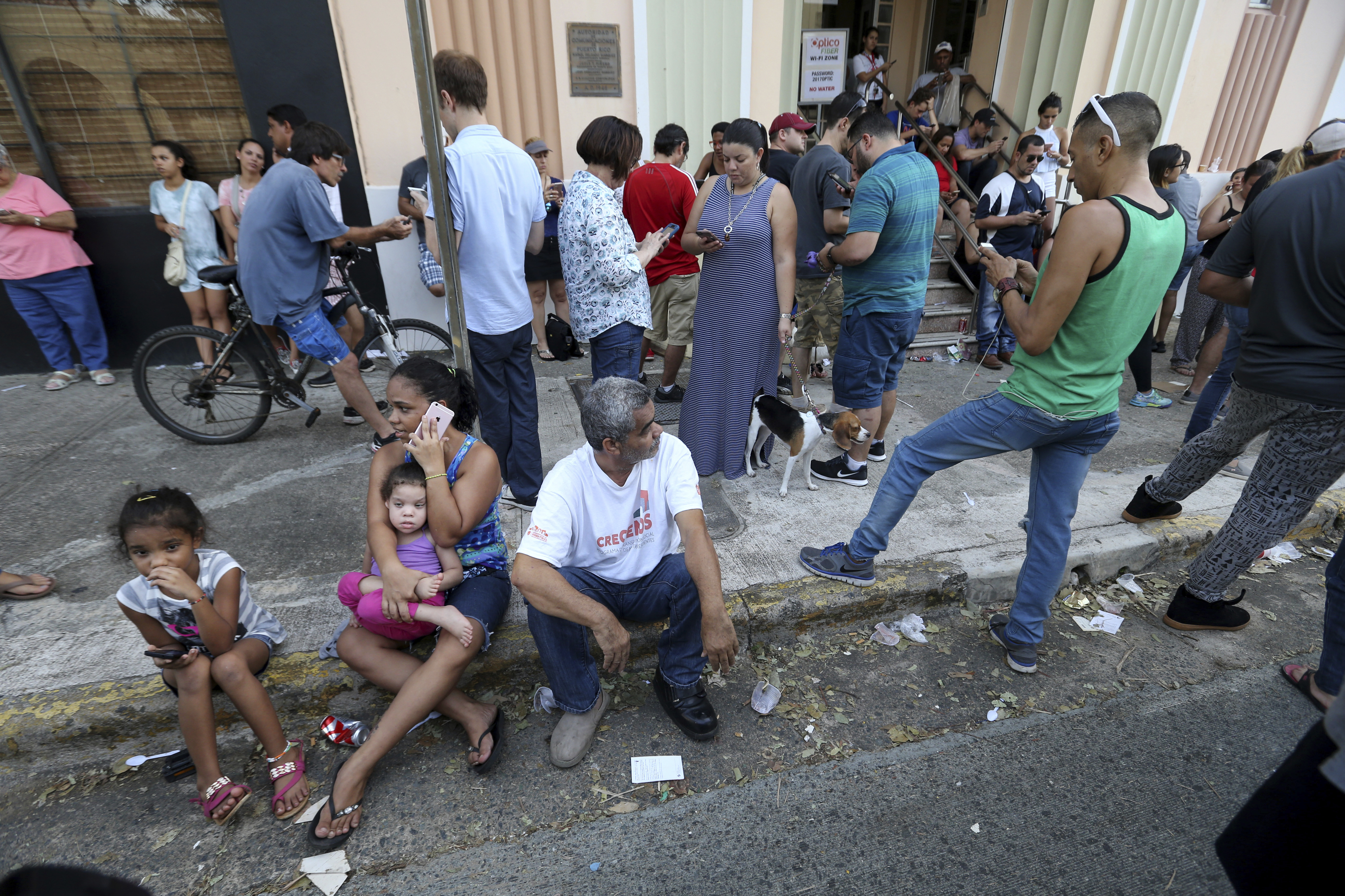 People use their devices to communicate as they congregate on the street at a wifi hotspot in San Juan, Puerto Rico, in the aftermath of Hurricane Maria, Sunday, Sept. 24, 2017. CREDIT: AP Photo/Gerald Herbert