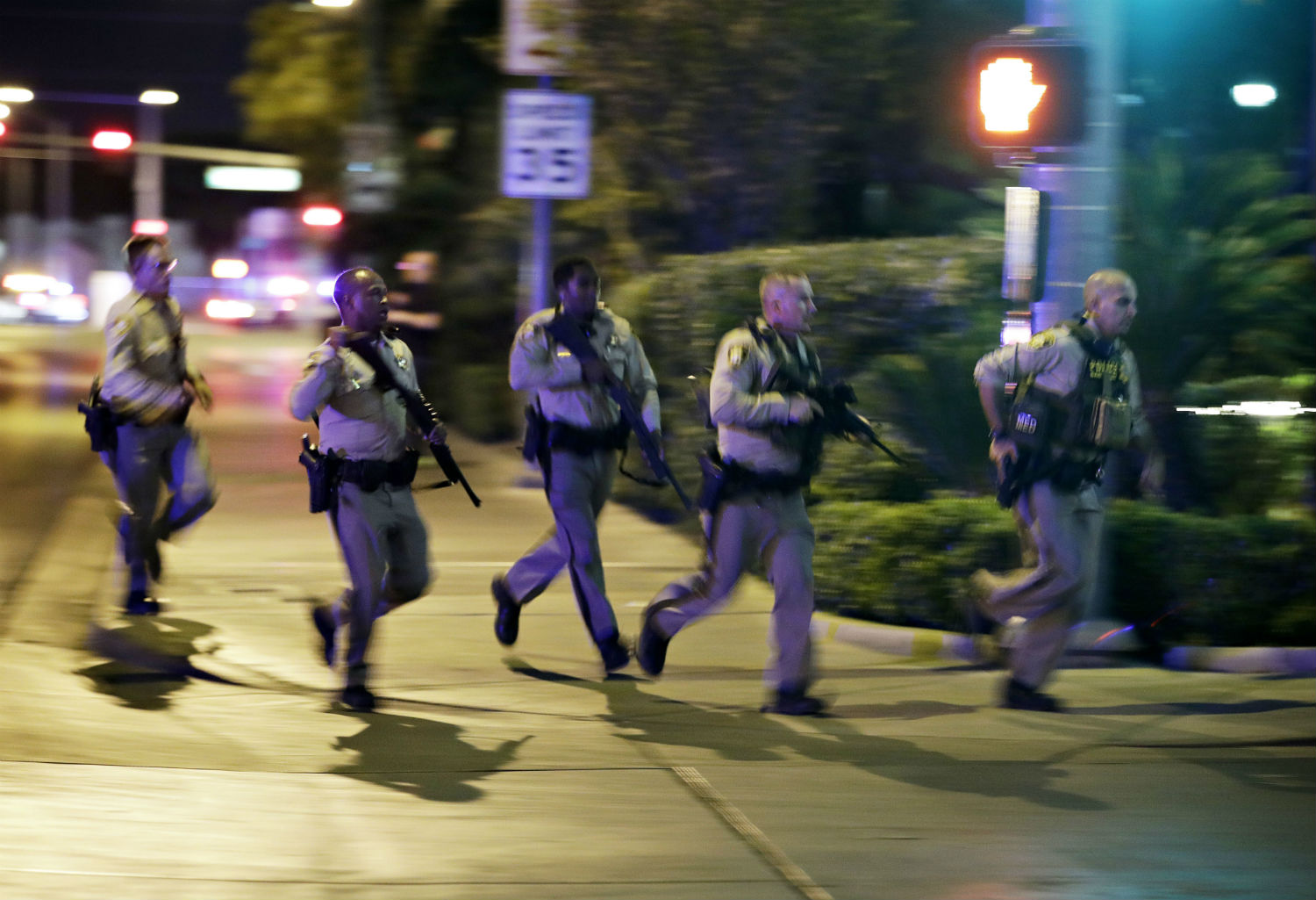 Police run to cover at the scene of a shooting near the Mandalay Bay resort and casino on the Las Vegas Strip on Sunday. (CREDIT: AP Photo/John Locher)