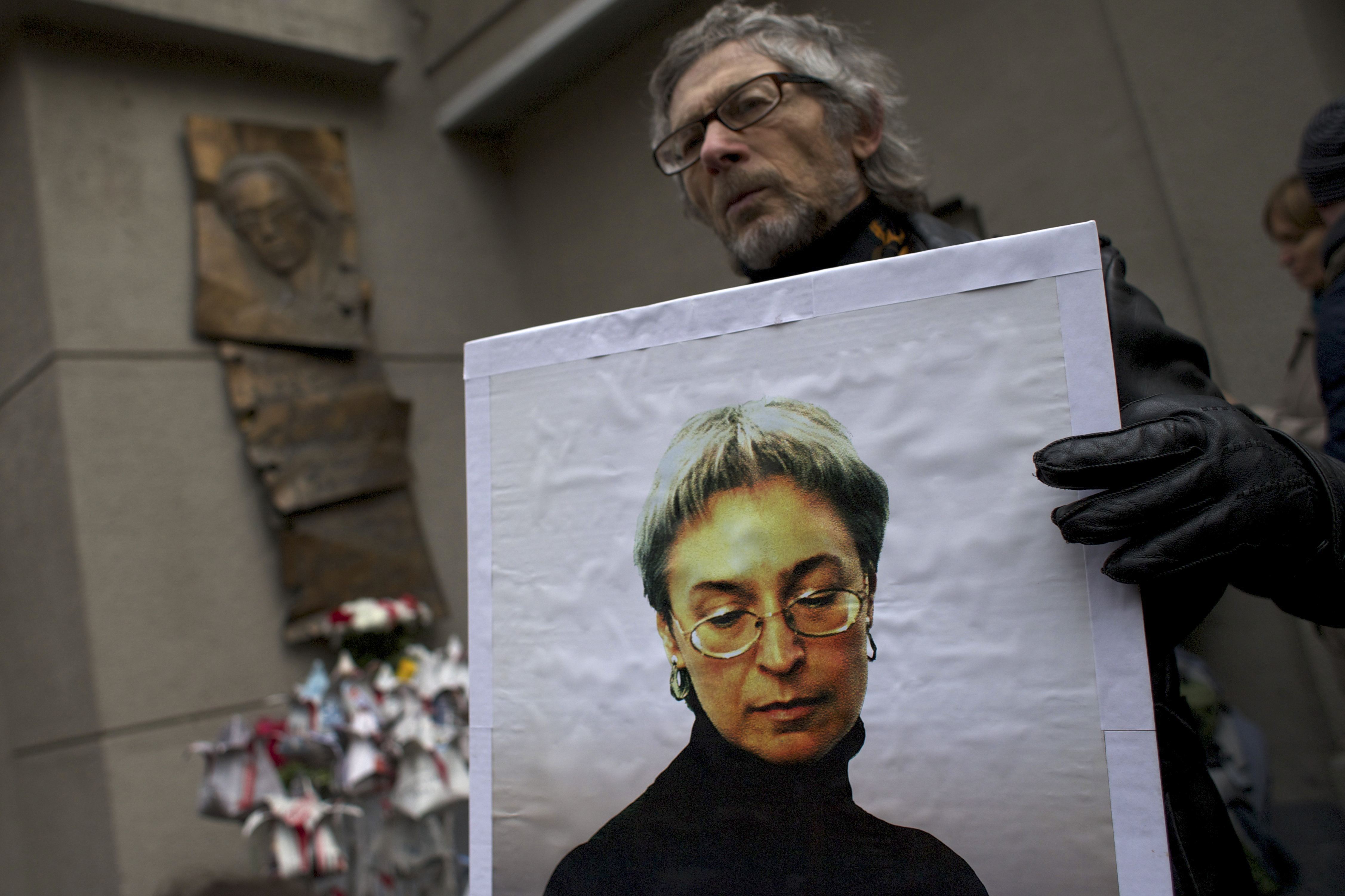 A man holds a portrait of Anna Politkovskaya, as people lay flowers made from newspapers to pay respect to Politkovskaya, journalist of Novaya Gazeta, outside Novaya Gazeta head office in Moscow, Russia, Tuesday, Oct. 7, 2014. CREDIT: AP Photo/Ivan Sekretarev