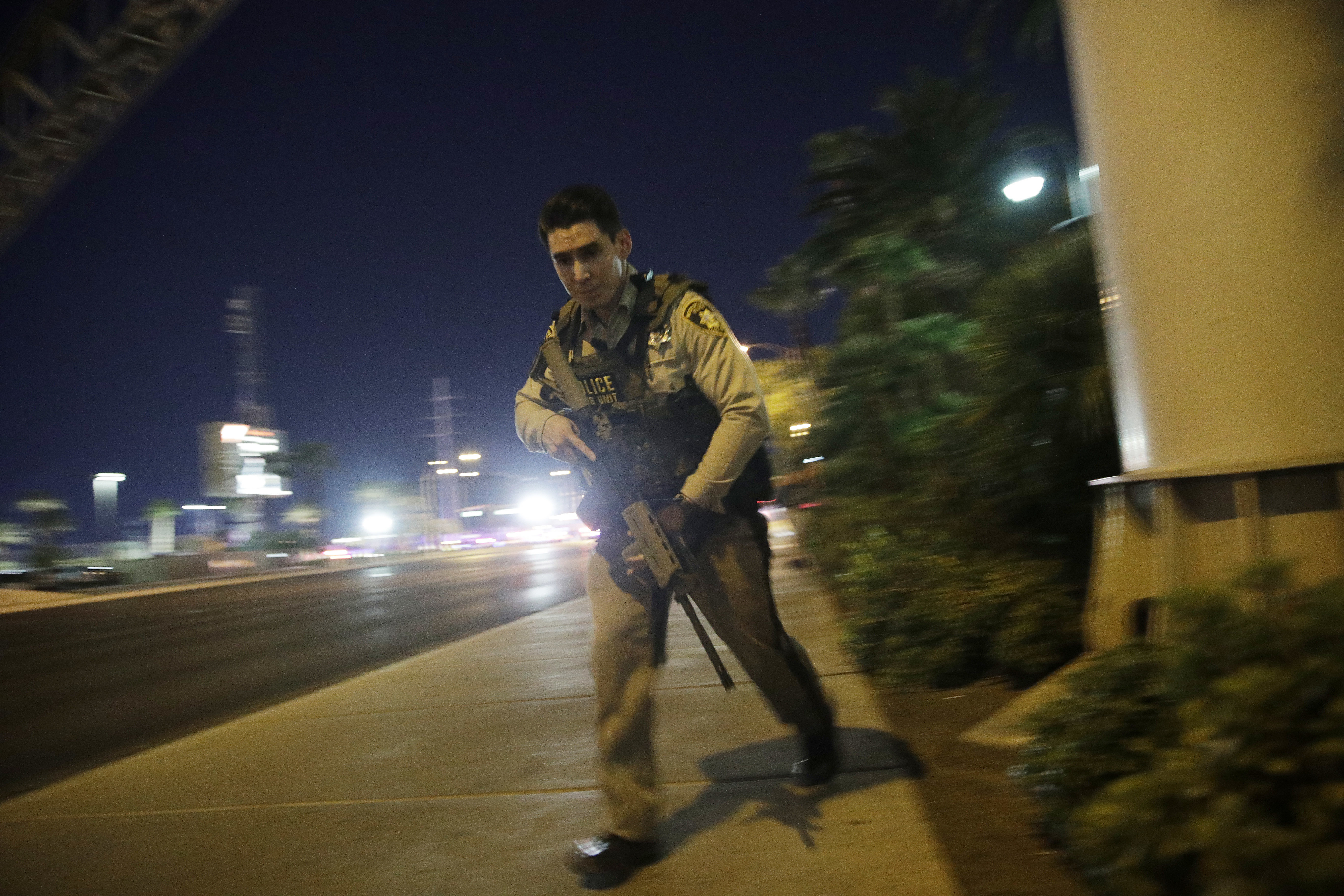 A police officer runs along a sidewalk near the scene of the Las Vegas shooting. CREDIT: AP Photo/John Locher