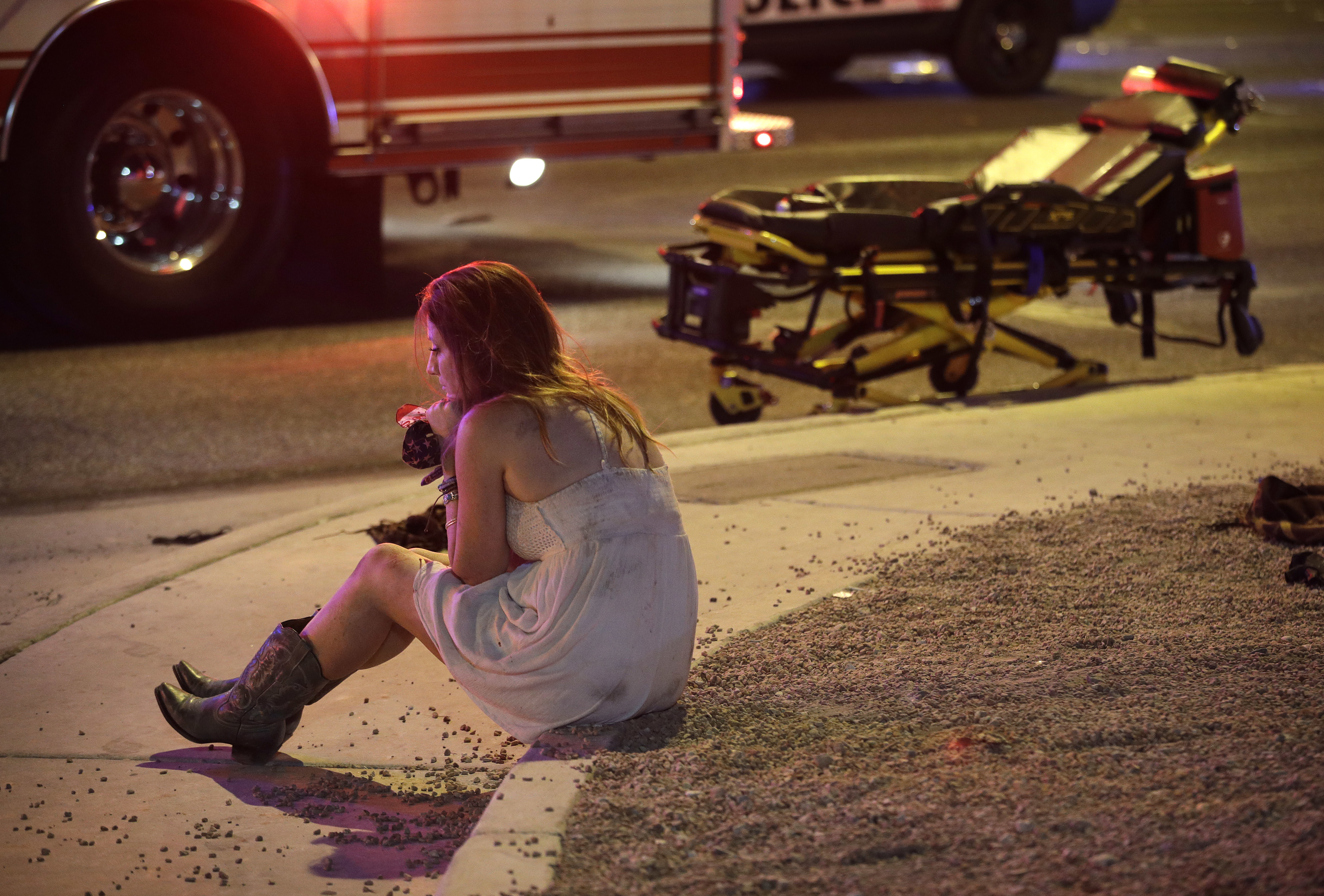 A woman sits on a curb at the scene of a shooting outside of a music festival along the Las Vegas Strip, Monday, Oct. 2, 2017, in Las Vegas. CREDIT: AP Photo/John Locher