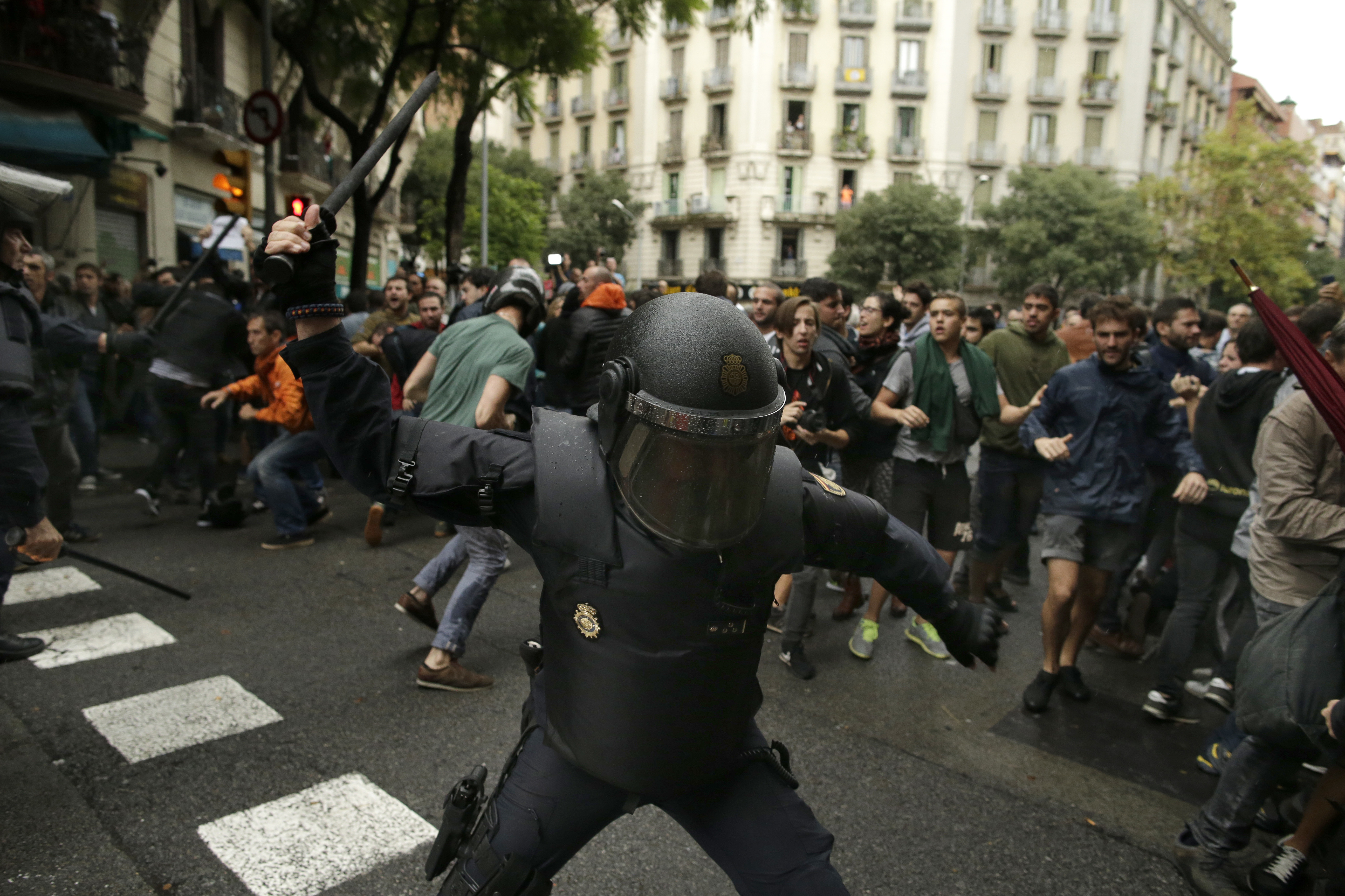 A Spanish riot police swings a club against would-be voters near a school assigned to be a polling station by the Catalan government in Barcelona, Spain, Sunday, Oct. 1, 2017. (CREDIT: AP Photo/Manu Fernandez, File)